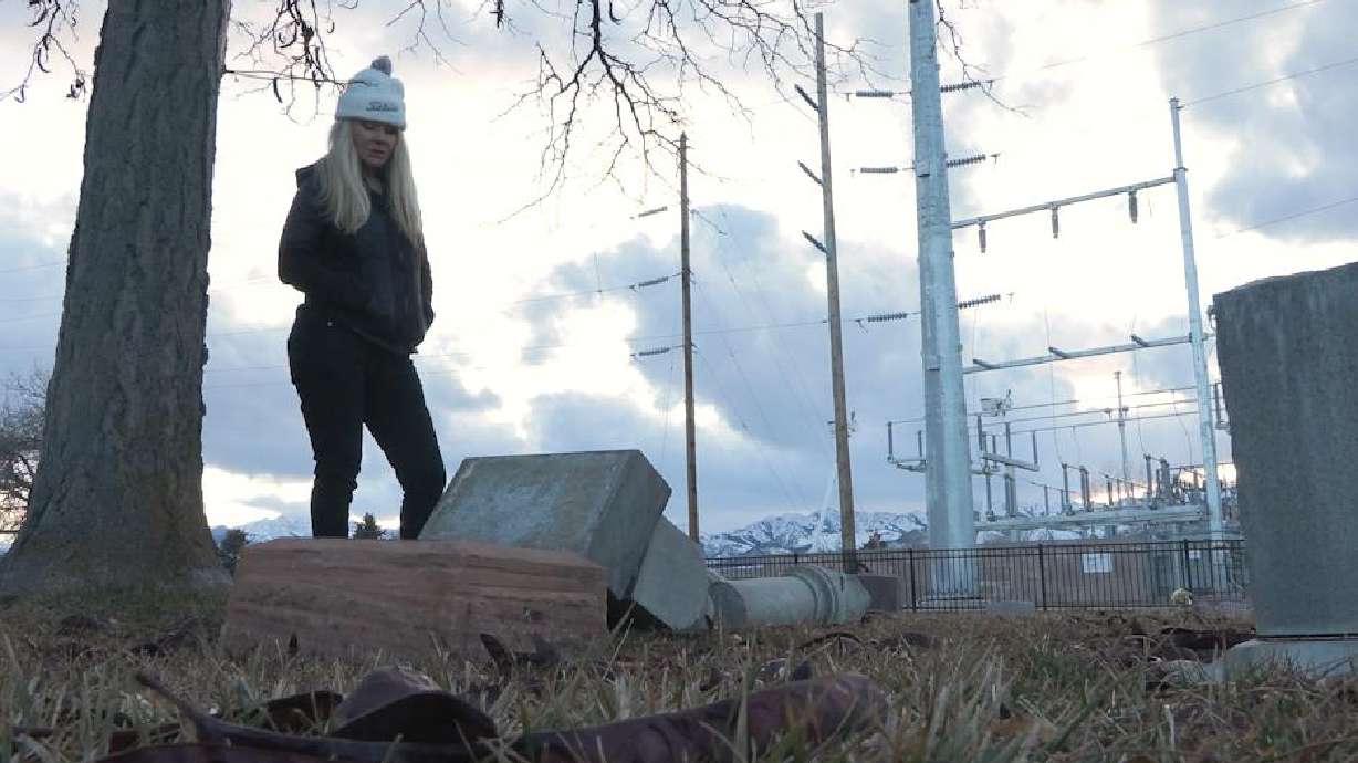 Susan Orifici stands over a broken headstone dating back to the late 1800s in Grantsville on Feb. 15. Representatives of several groups met to discuss repairing the headstones