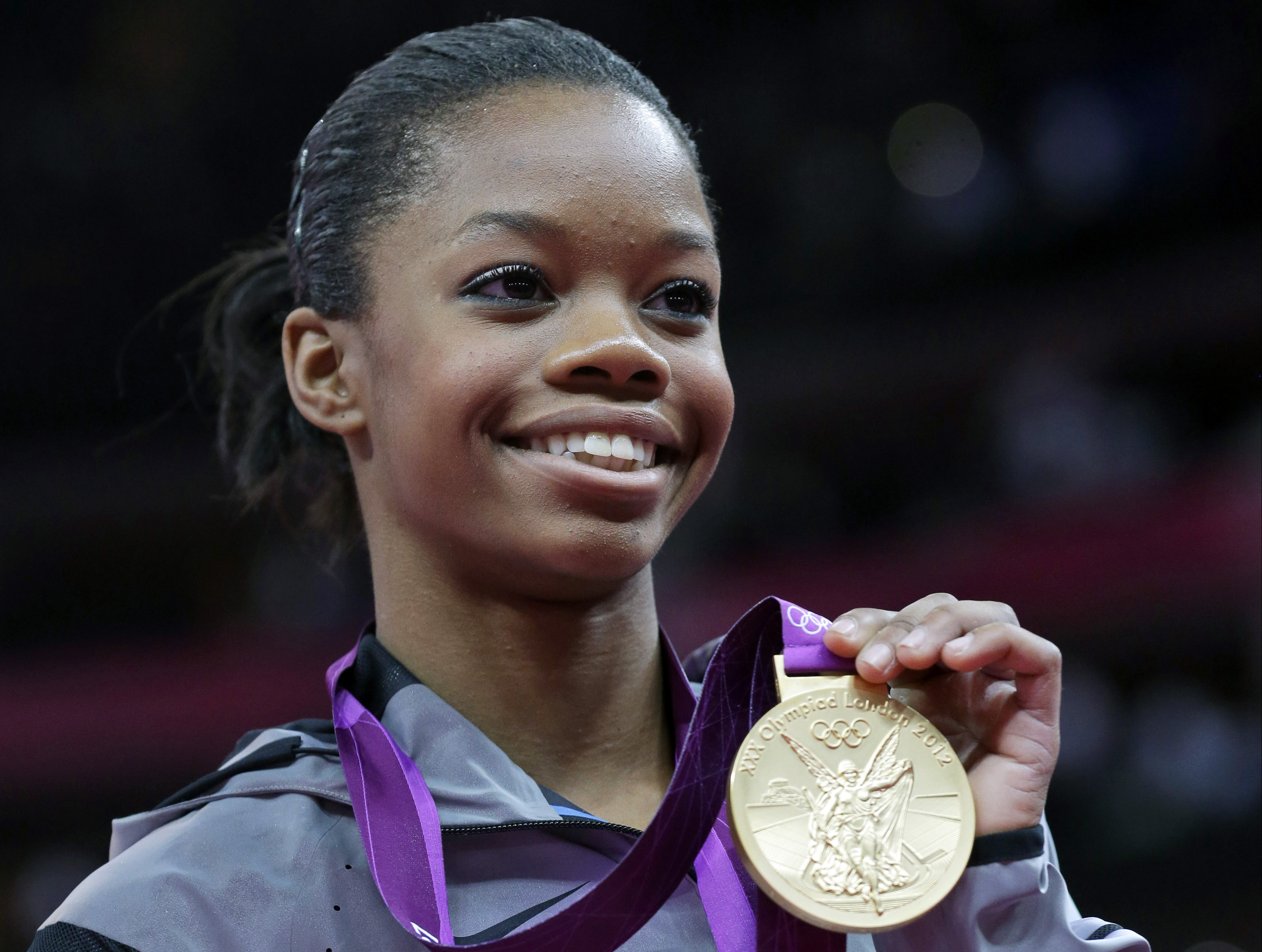 FILE - U.S. gymnast Gabby Douglas displays her gold medal during the artistic gymnastics women's individual all-around competition at the 2012 Summer Olympics in London, Aug. 2, 2012. Douglas pulled out of this weekend's 2024 Winter Cup in Louisville after testing positive for COVID-19. The meet was to be Douglas' first competition since the 2016 Olympics
