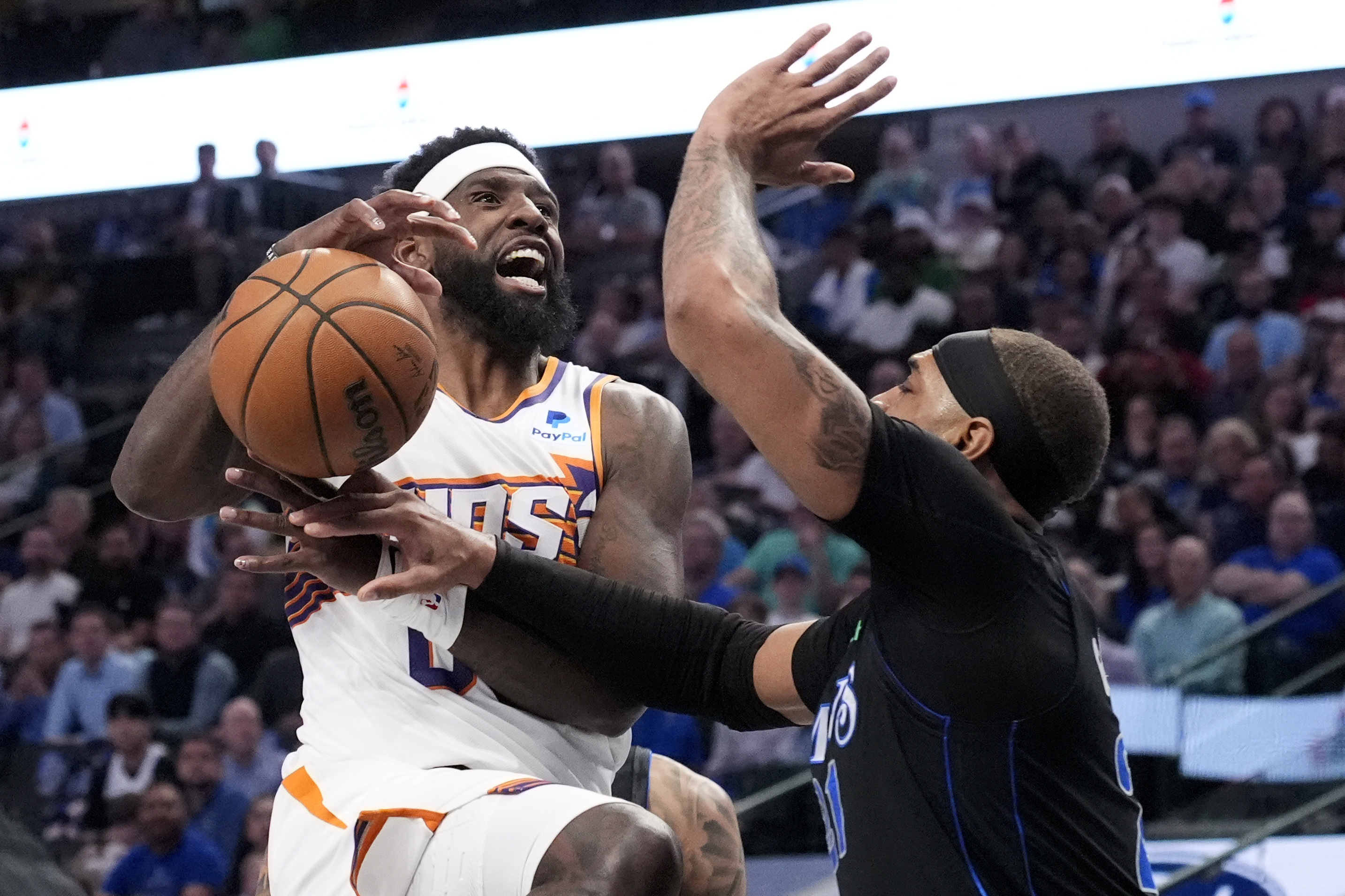 Phoenix Suns forward Royce O'Neale, left, loses control of the ball on a drive to the basket as Dallas Mavericks' Daniel Gafford, right, defends in the first half of an NBA basketball game in Dallas, Thursday, Feb. 22, 2024. 
