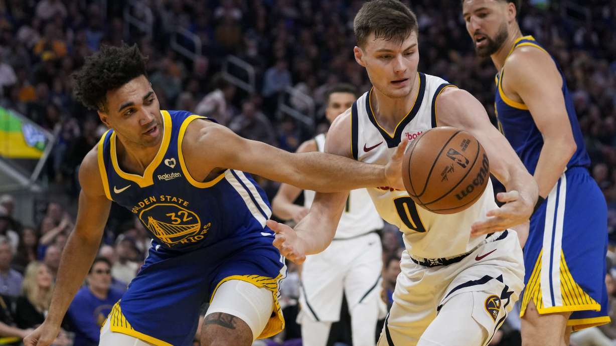 Golden State Warriors forward Trayce Jackson-Davis, left, and Denver Nuggets guard Christian Braun (0) compete for possession of the ball during the first half of an NBA basketball game Sunday, Feb. 25, 2024, in San Francisco.