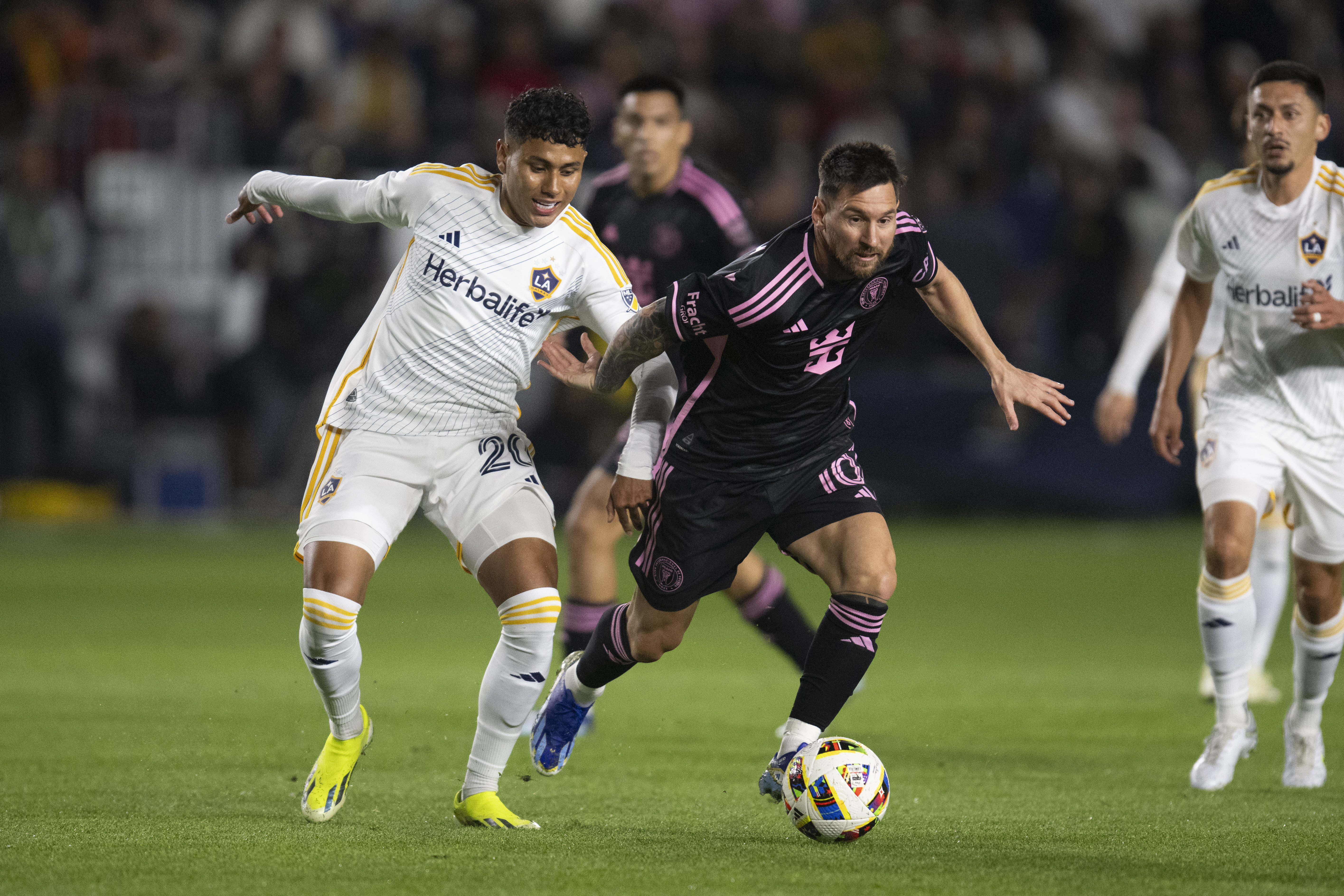 CORRECTS TO SUNDAY NOT SATURDAY - Inter Miami forward Lionel Messi (10) dribbles the ball past Los Angeles Galaxy midfielder Edwin Cerrillo (20) during the first half of an MLS soccer match, Sunday, Feb. 25, 2024, in Carson, Calif.