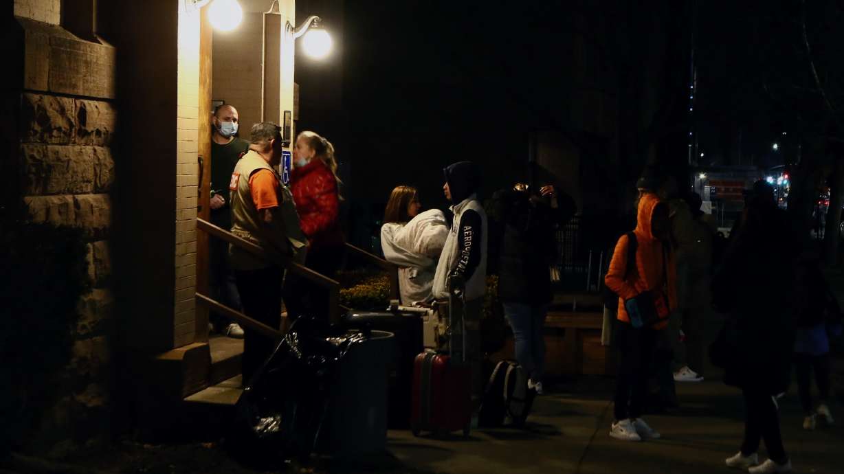 A Venezuelan family of nine stands on the steps at the First United Methodist Church in Salt Lake, after arriving from New York City without shelter.