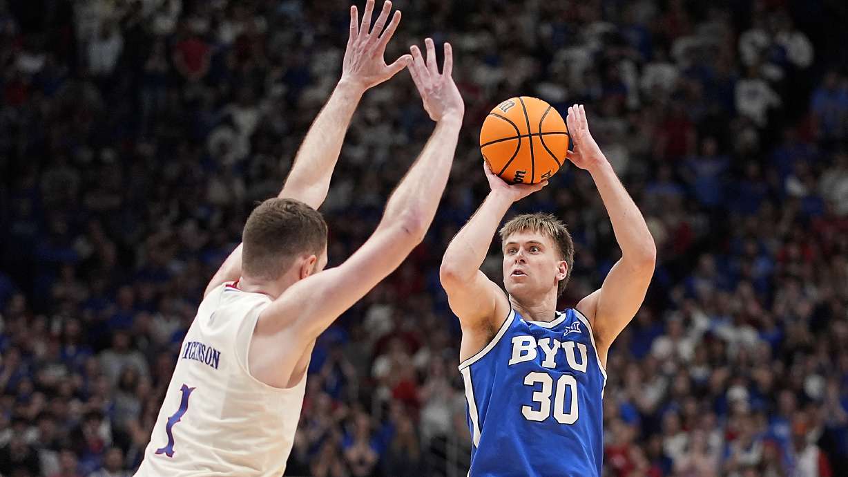 BYU guard Dallin Hall (30) shoots over Kansas center Hunter Dickinson (1) during the second half of an NCAA college basketball game Tuesday, Feb. 27, 2024, in Lawrence, Kan. BYU won 76-68.