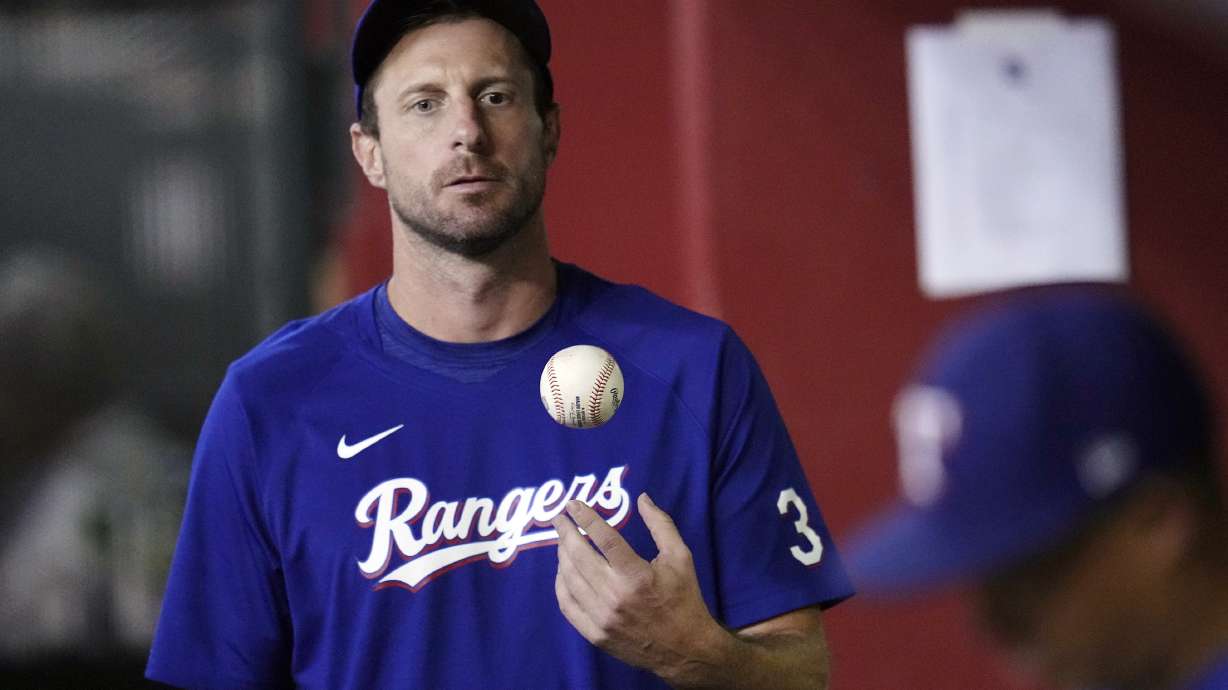 FILE- Texas Rangers' Max Scherzer flips the ball in the air as he paces the dugout during the seventh inning of a baseball game against the Arizona Diamondbacks Tuesday, Aug. 22, 2023, in Phoenix. Scherzer logged at least 179 innings in 10 of his first 16 years in the majors. And the three-time Cy Young Award winner learned some tough lessons on the road to pitching deep into games. That's one reason why the Rangers right-hander thinks Major League Baseball needs to look a lot deeper than a roster limit if it wants to return starting pitching to prominence.