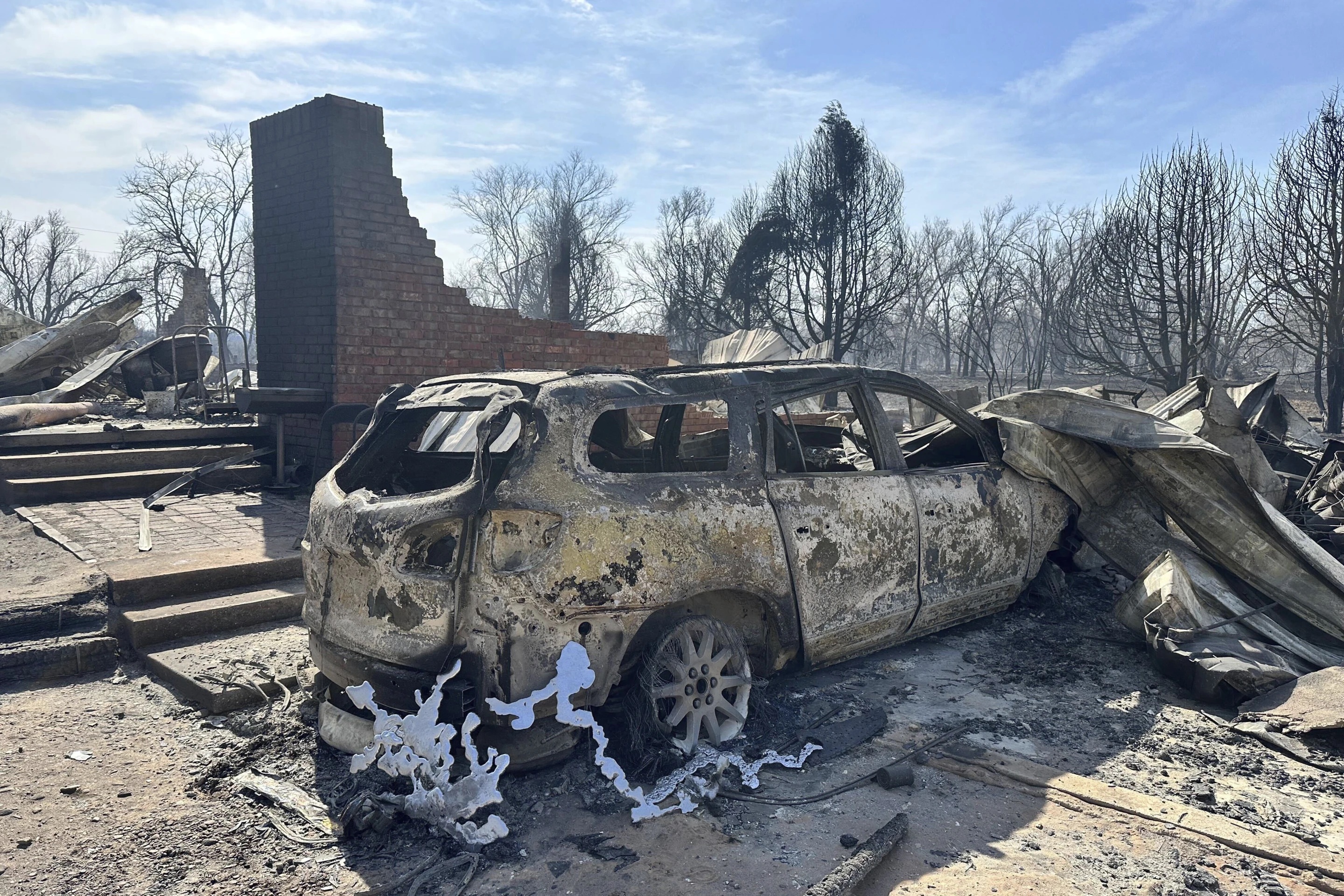 A burned car rests near the charred remains of a home outside of Canadian, Texas Wednesday after a wildfire passed. A fast-moving wildfire burning through the Texas Panhandle grew into the second-largest blaze in state history Wednesday, forcing evacuations and triggering power outages as firefighters struggled to contain the widening flames.