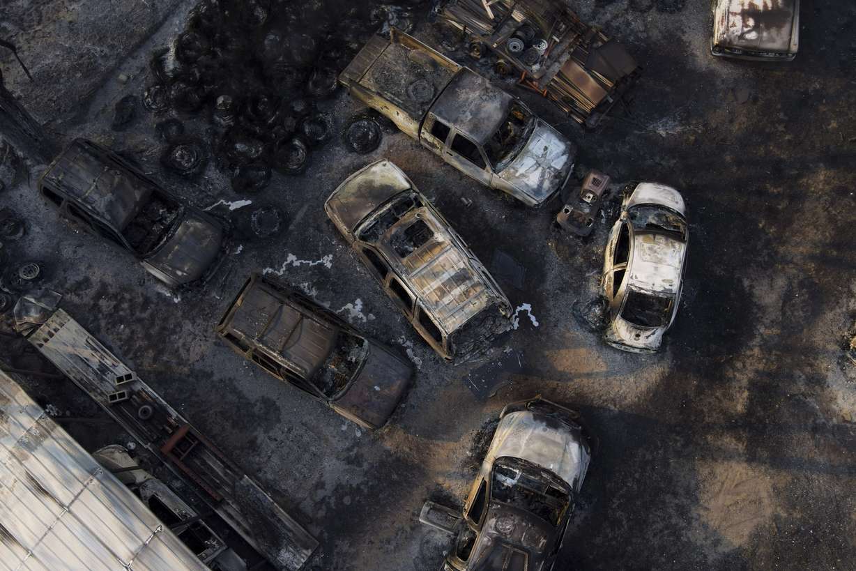 Charred vehicles sit at an auto body shop after the property was burned by the Smokehouse Creek Fire, Wednesday in Canadian, Texas.