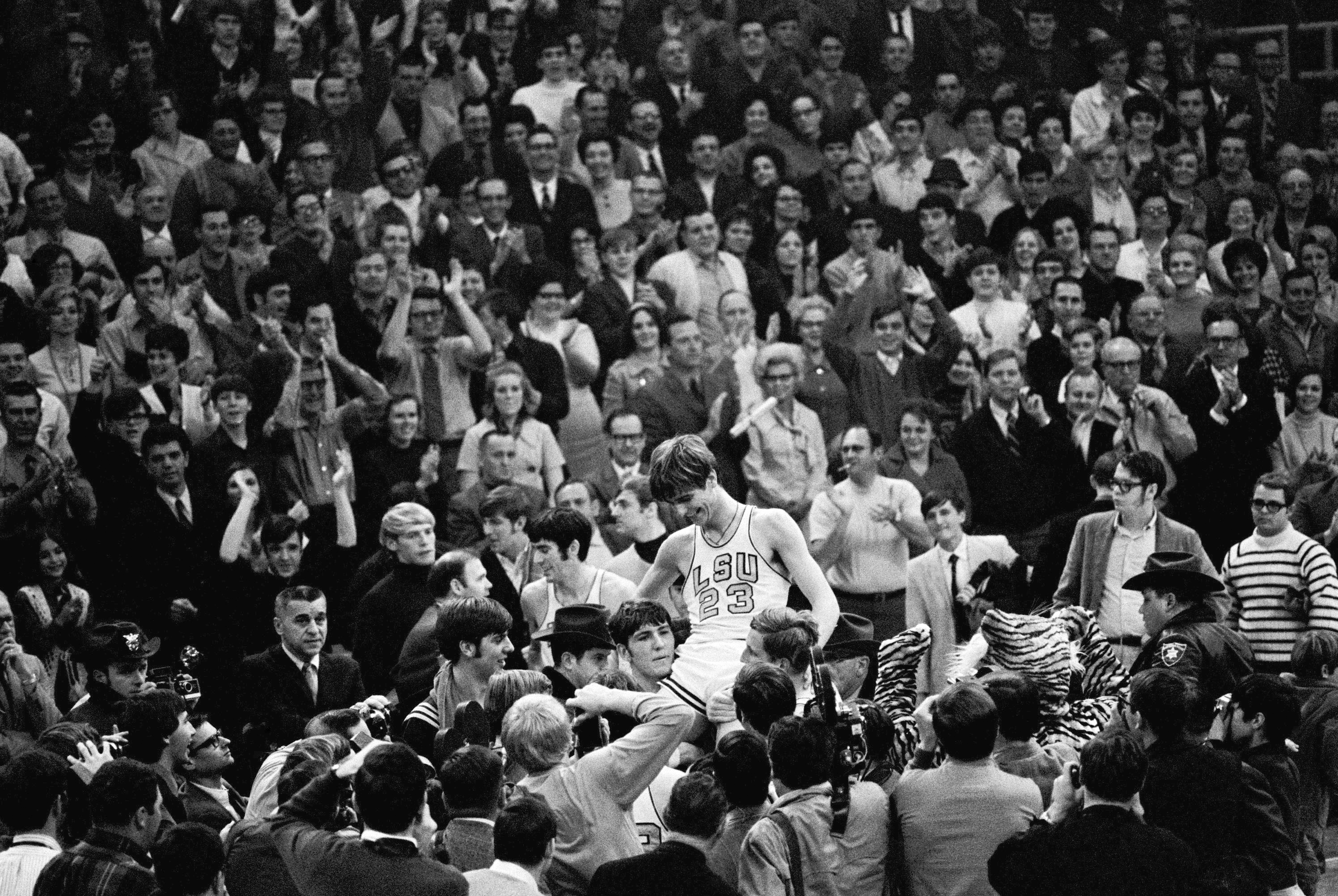 THIS CORRECTS THE DATE TO JAN. 31, 1970, NOT JAN. 28, 1979, AS ORIGINALLY SENT - - FILE - Pete Maravich (23) gets a boost from players and fans after he broke the all-time scoring record in Baton Rouge, La., Jan. 31, 1970. Calmly looking on at far left center is Pete's dad, Press, who coaches the Louisiana State Tigers. Those who played with, followed or knew the late Maravich are conflicted about the seemingly inevitable moment — likely this Sunday — when he could be supplanted by Iowa women's basketball sensation Caitlin Clark atop the NCAA's all-time scoring list. 