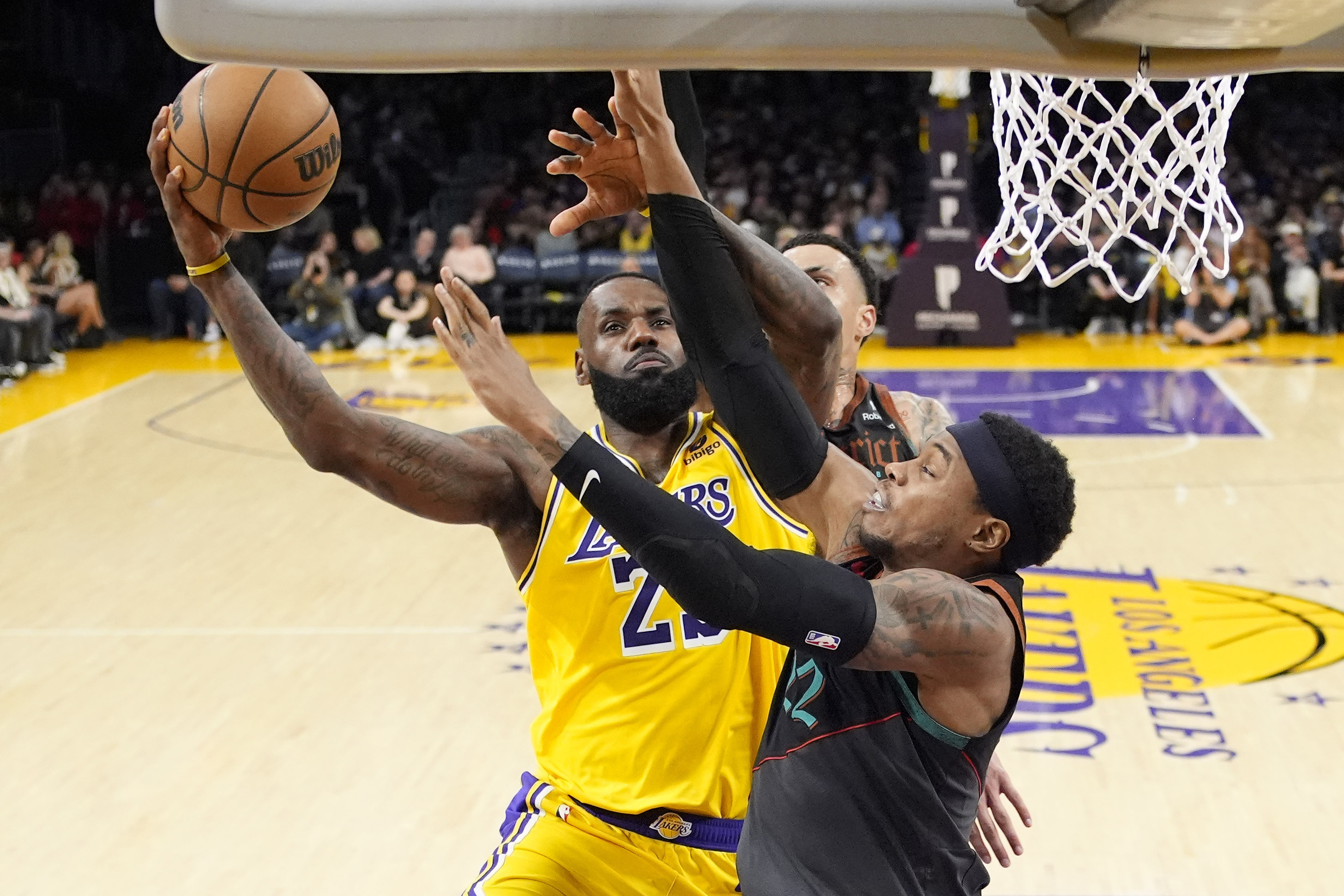 Los Angeles Lakers forward LeBron James, left, shoots as Washington Wizards forward Kyle Kuzma, center, and forward Richaun Holmes defend during the second half of an NBA basketball game Thursday, Feb. 29, 2024, in Los Angeles. 
