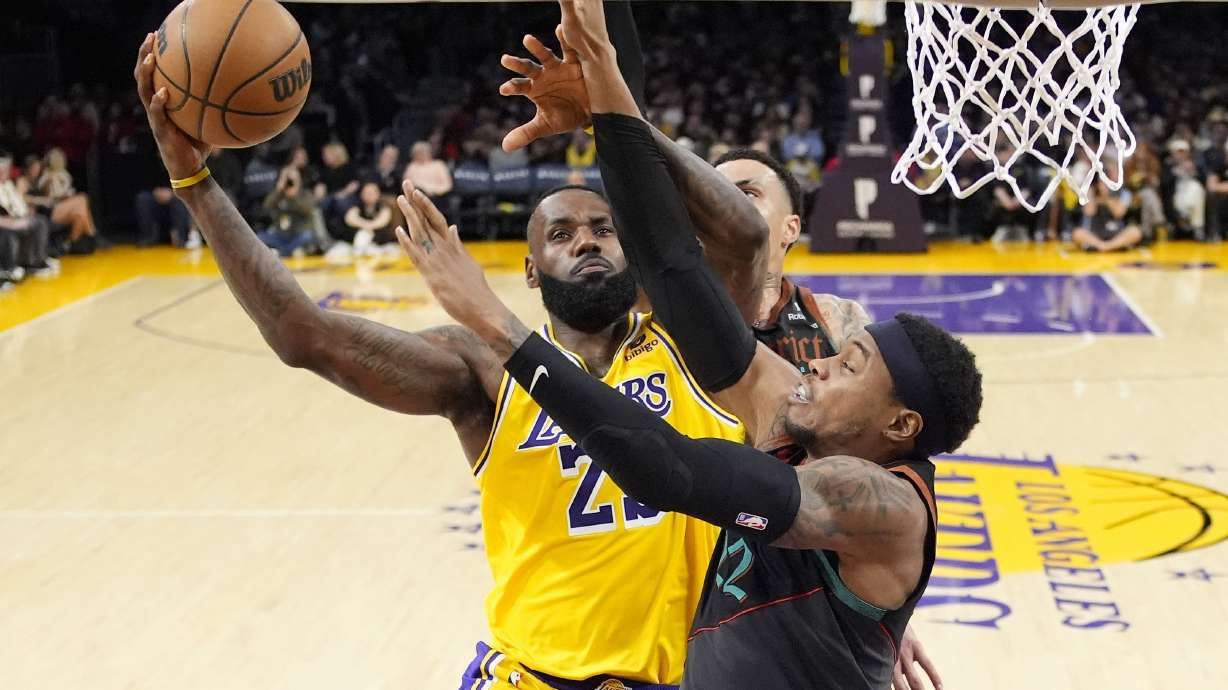 Los Angeles Lakers forward LeBron James, left, shoots as Washington Wizards forward Kyle Kuzma, center, and forward Richaun Holmes defend during the second half of an NBA basketball game Thursday, Feb. 29, 2024, in Los Angeles.