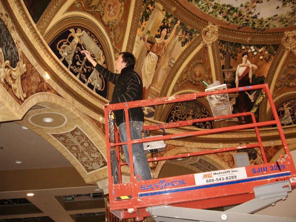 Andrew Zabela-Zabelin paints a wall mural, location and date not specified.