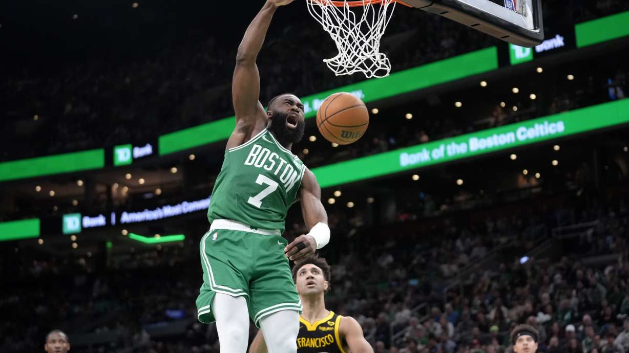 Boston Celtics guard Jaylen Brown (7) dunks the ball to score in front of Golden State Warriors forward Trayce Jackson-Davis (32) in the second half of an NBA basketball game, Sunday, March 3, 2024, in Boston.