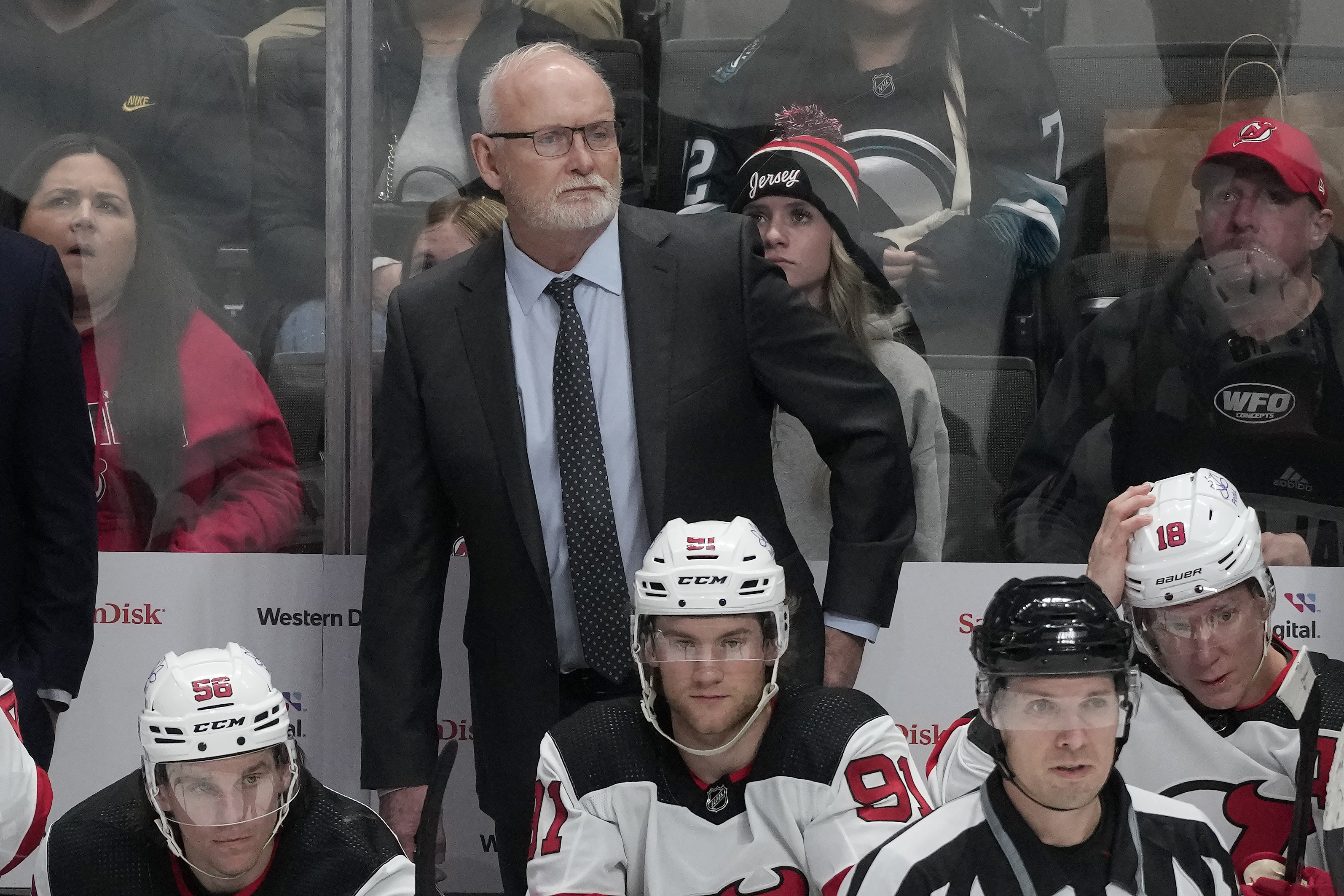 New Jersey Devils coach Lindy Ruff, standing, watches from the bench during the third period of the team's NHL hockey game against the San Jose Sharks in San Jose, Calif., Tuesday, Feb. 27, 2024.