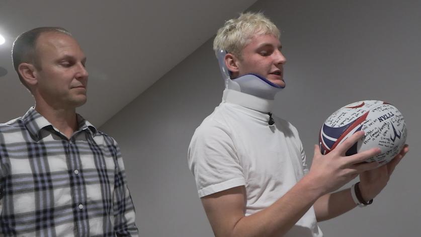 Ben and Rylan Southwick look at a rugby ball signed with well wishes.