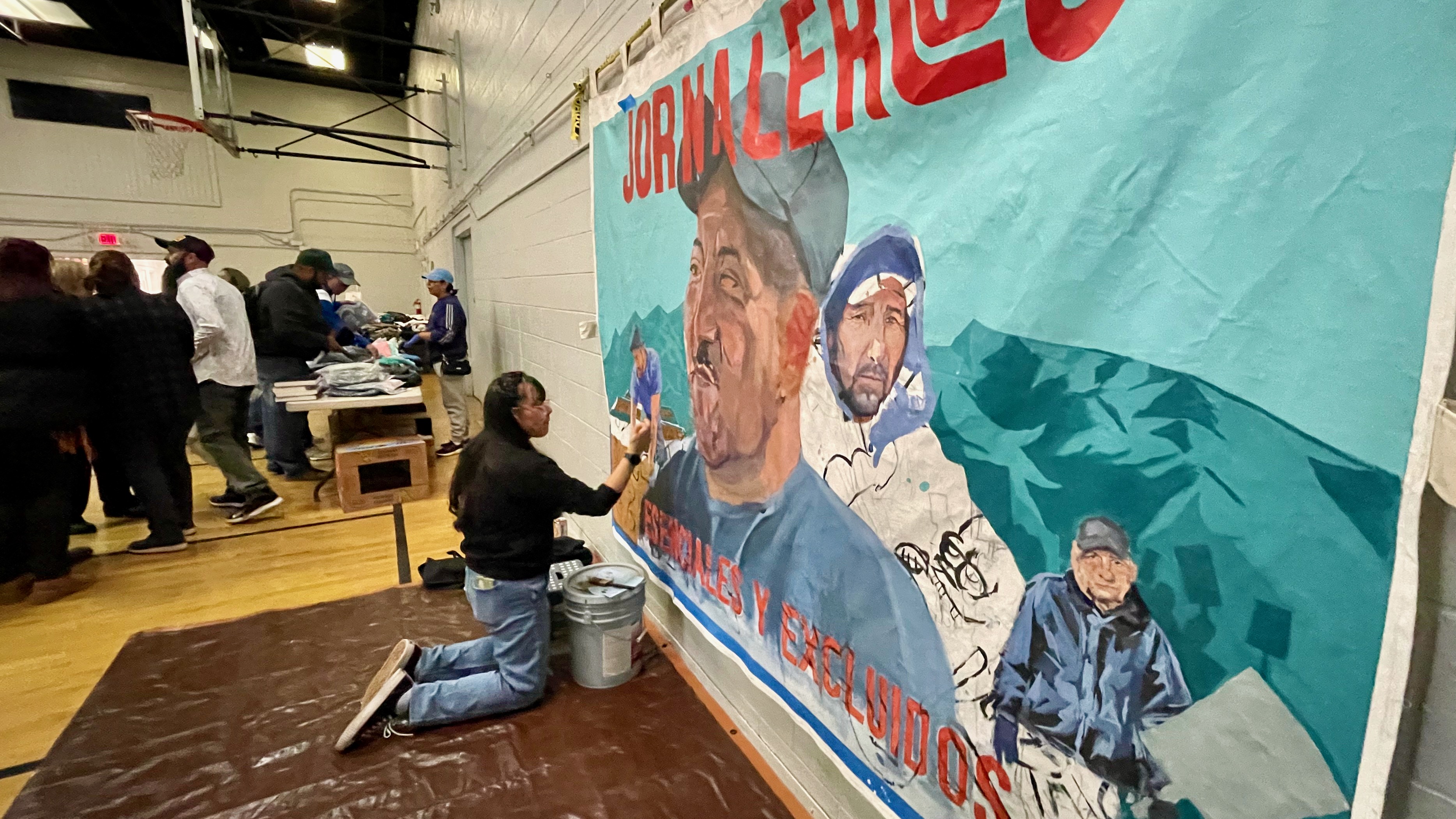 Sarai Santiago works on a poster at the Mexican Civic Center in Salt Lake City on Wednesday, at an event in support of day laborers. The poster reads, in English, "Laborers" across the top and "Essential and excluded" across the bottom.