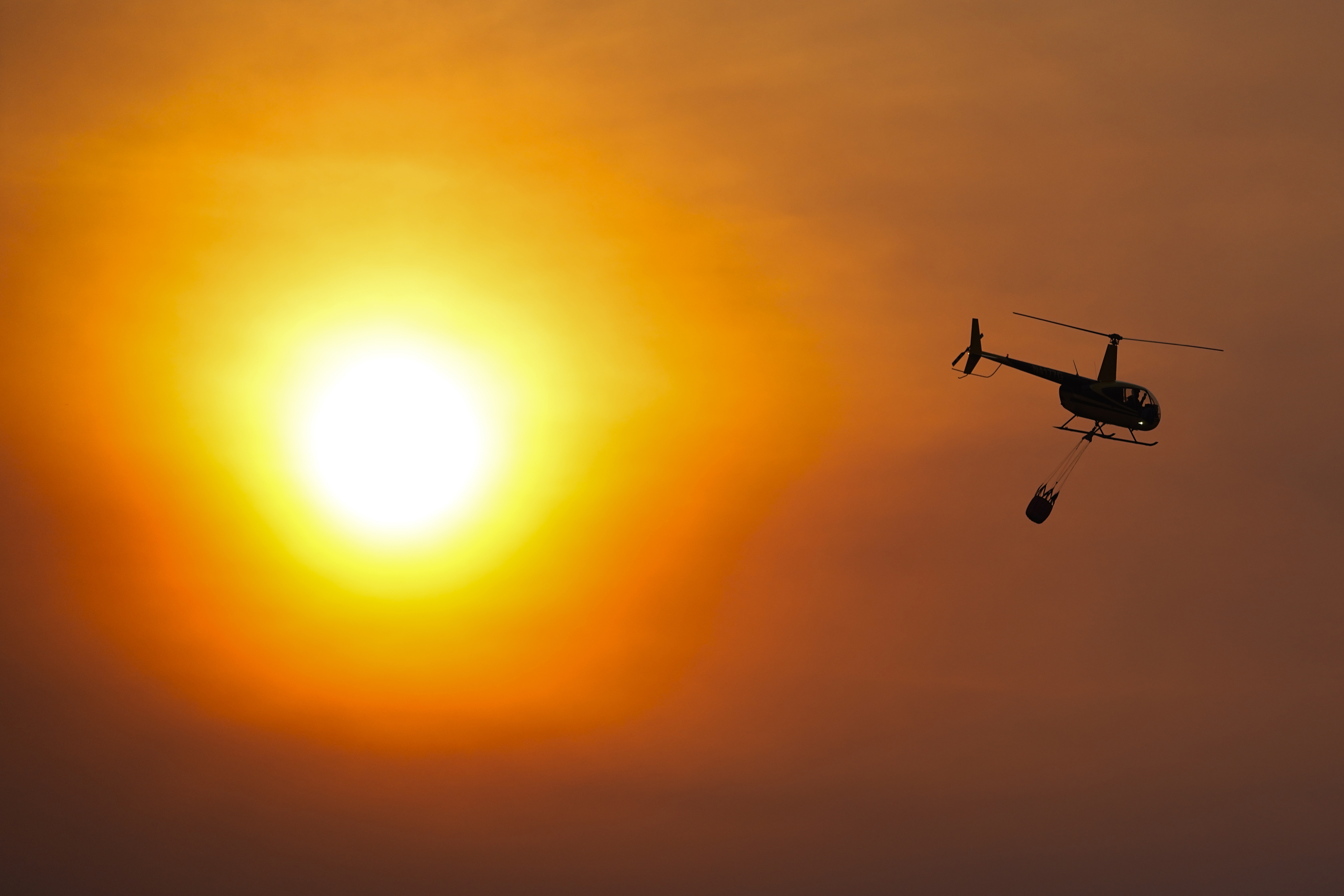 A helicopter carries a bucket as it flies over homes burned by the Smokehouse Creek Fire, Feb. 28, in Canadian, Texas. The utility provider Xcel Energy says Thursday its facilities appeared to have played a role in igniting a massive wildfire.