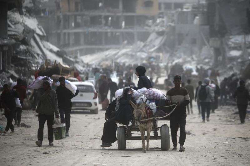 Palestinians carry their belongings after visiting their houses destroyed in the Israeli offensive on Khan Younis, Gaza Strip, Wednesday.