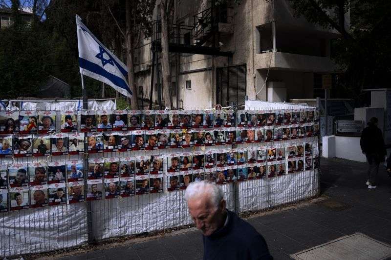 People pass by a fence with photographs of Israelis who are being held hostage in the Gaza Strip by the Hamas militant group, in Ramat Gan, Israel, Thursday.