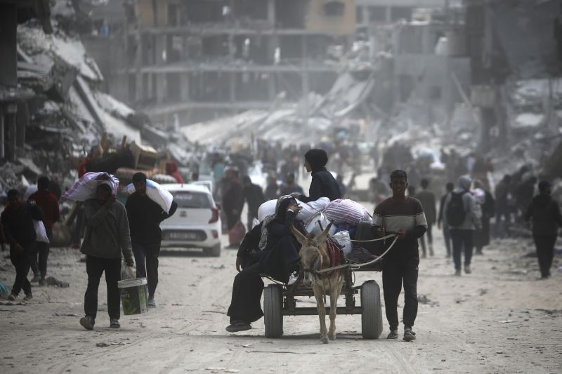 Palestinians carry their belongings after visiting their houses destroyed in the Israeli offensive on Khan Younis, Gaza Strip, Wednesday.