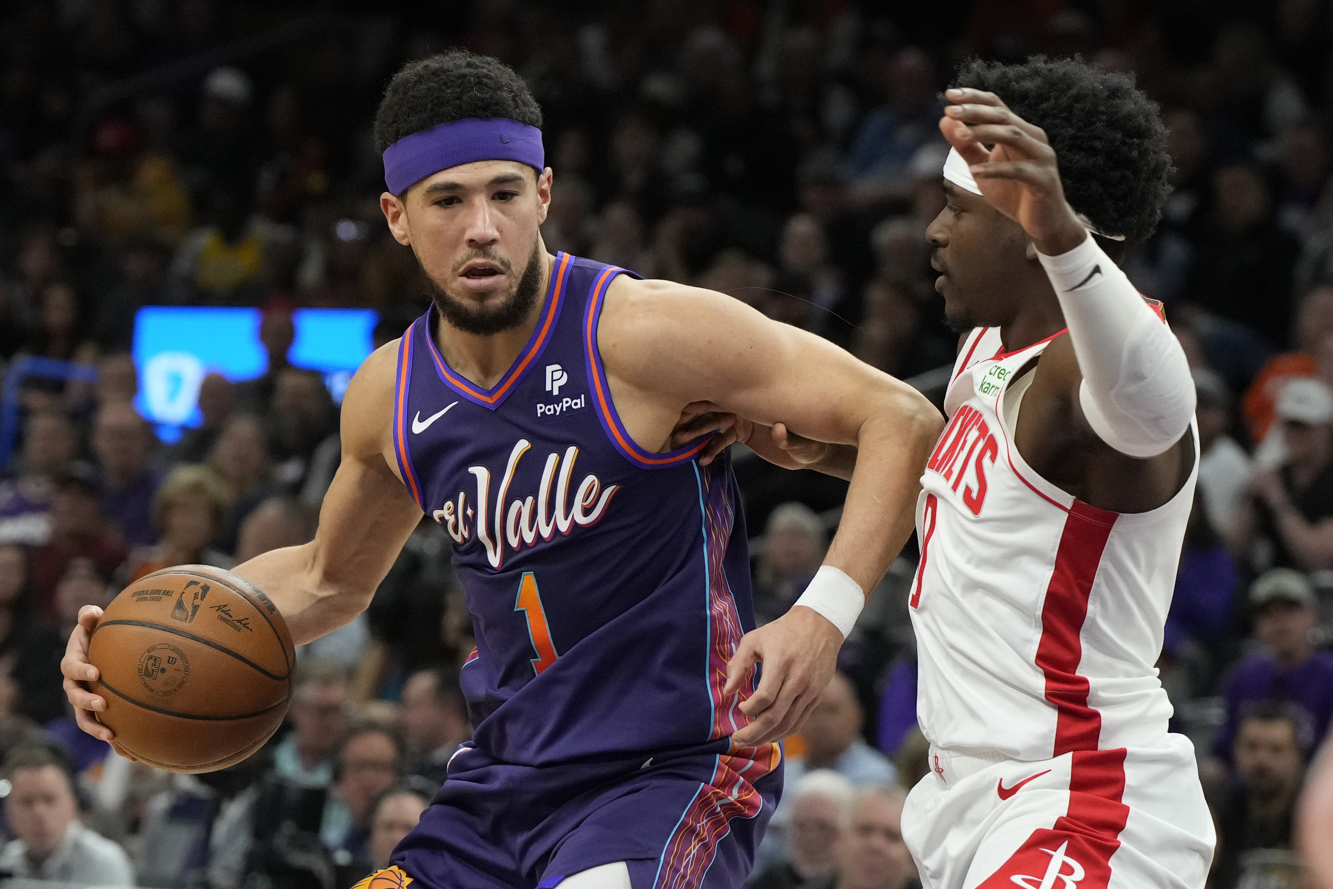 Phoenix Suns guard Devin Booker (1) drives against Houston Rockets guard Aaron Holiday, right, during the first half of an NBA basketball game, Thursday, Feb. 29, 2024, in Phoenix. 