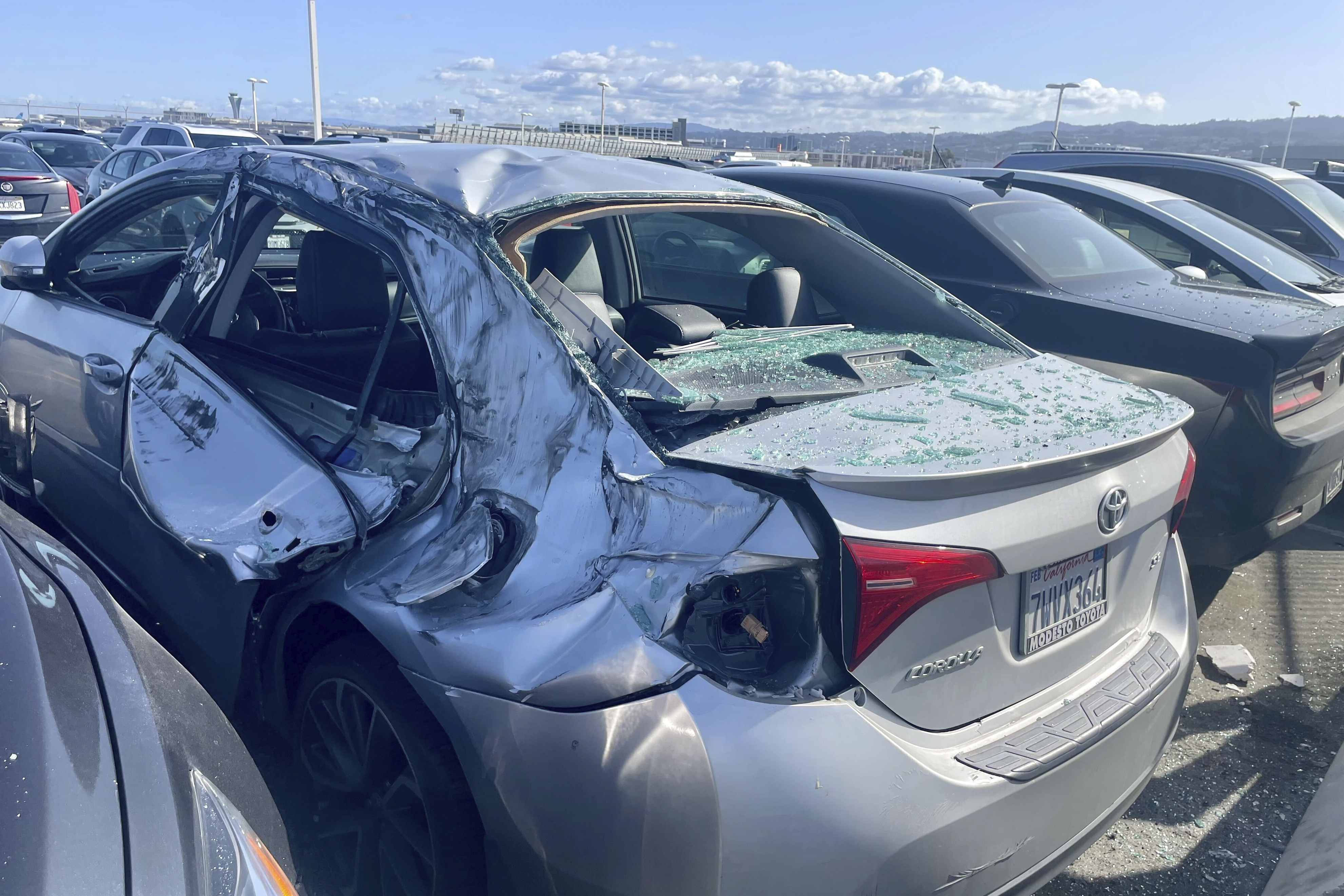 A damaged car is seen in an on-airport employee parking lot after tire debris from a Boeing 777 landed on it at San Francisco International Airport, Thursday. The jetliner bound for Japan made a safe landing in Los Angeles.