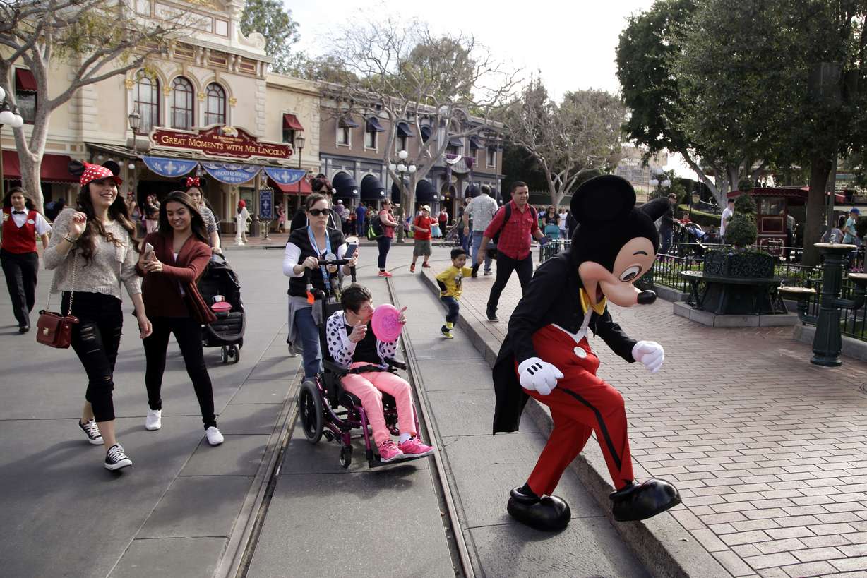 Visitors follow Mickey Mouse for photos at Disneyland, Jan. 22, 2015, in Anaheim, Calif. Disney is seeking approval from local officials to expand its California theme park offerings over the next four decades.