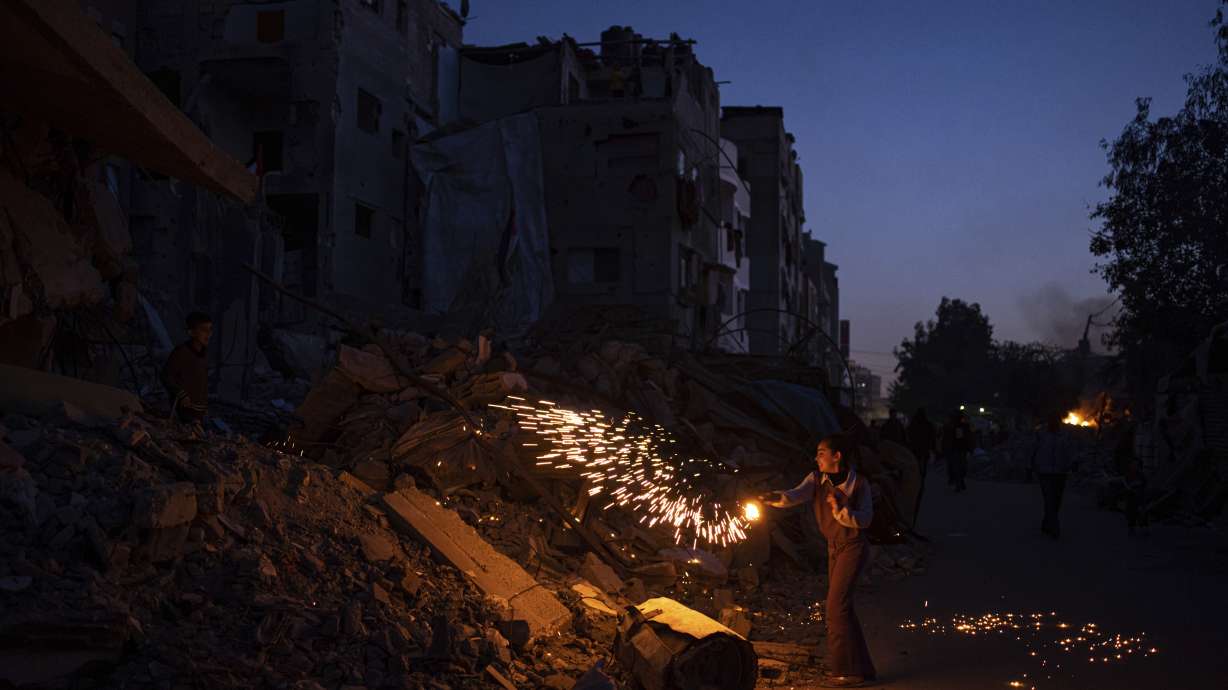 A Palestinian boy plays with fireworks as he celebrates the start of the Muslim holy month of Ramadan next to a destroyed residential building by the Israeli airstrikes in Rafah, Gaza Strip, Sunday.