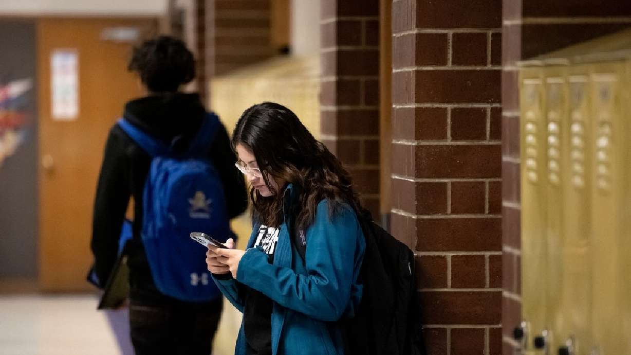 Sarah Valle, 17, uses her phone between classes at Cyprus High School in Magna on Jan. 27, 2023. Many teens acknowledge that they spend "too much" time on their devices.