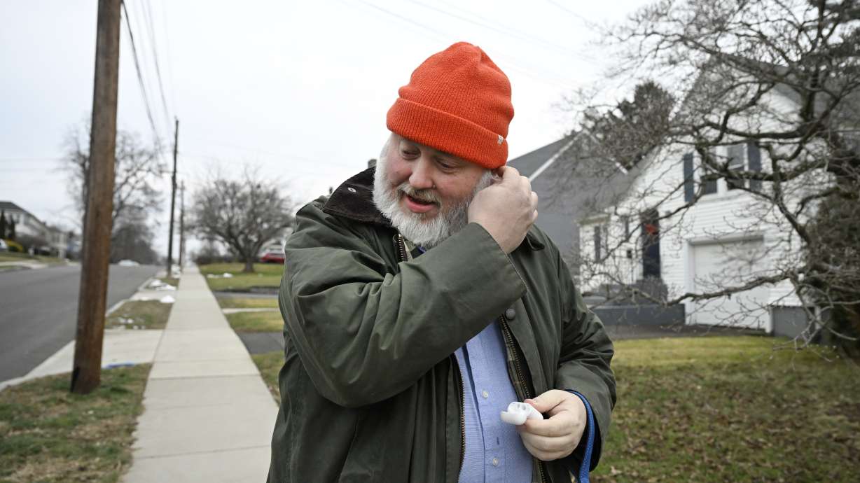 Casey Rosseau places earbuds in his ears to listen to an e-book while he walks with his dog in West Hartford, Conn., Feb. 1. Rosseau said he'd like to see more regulation of what publishers can charge libraries.