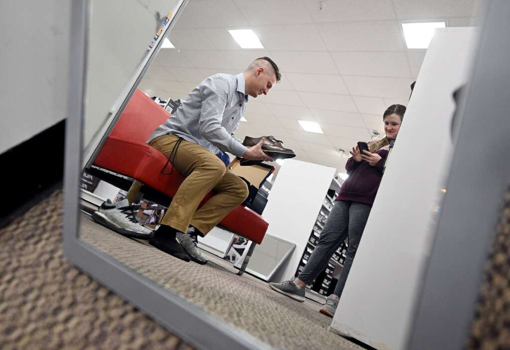 Cole Warner tries on shoes as he and other Weber State students, faculty and alumni take part in the Suit-Up sale at JCPenny in Riverdale on Tuesday.