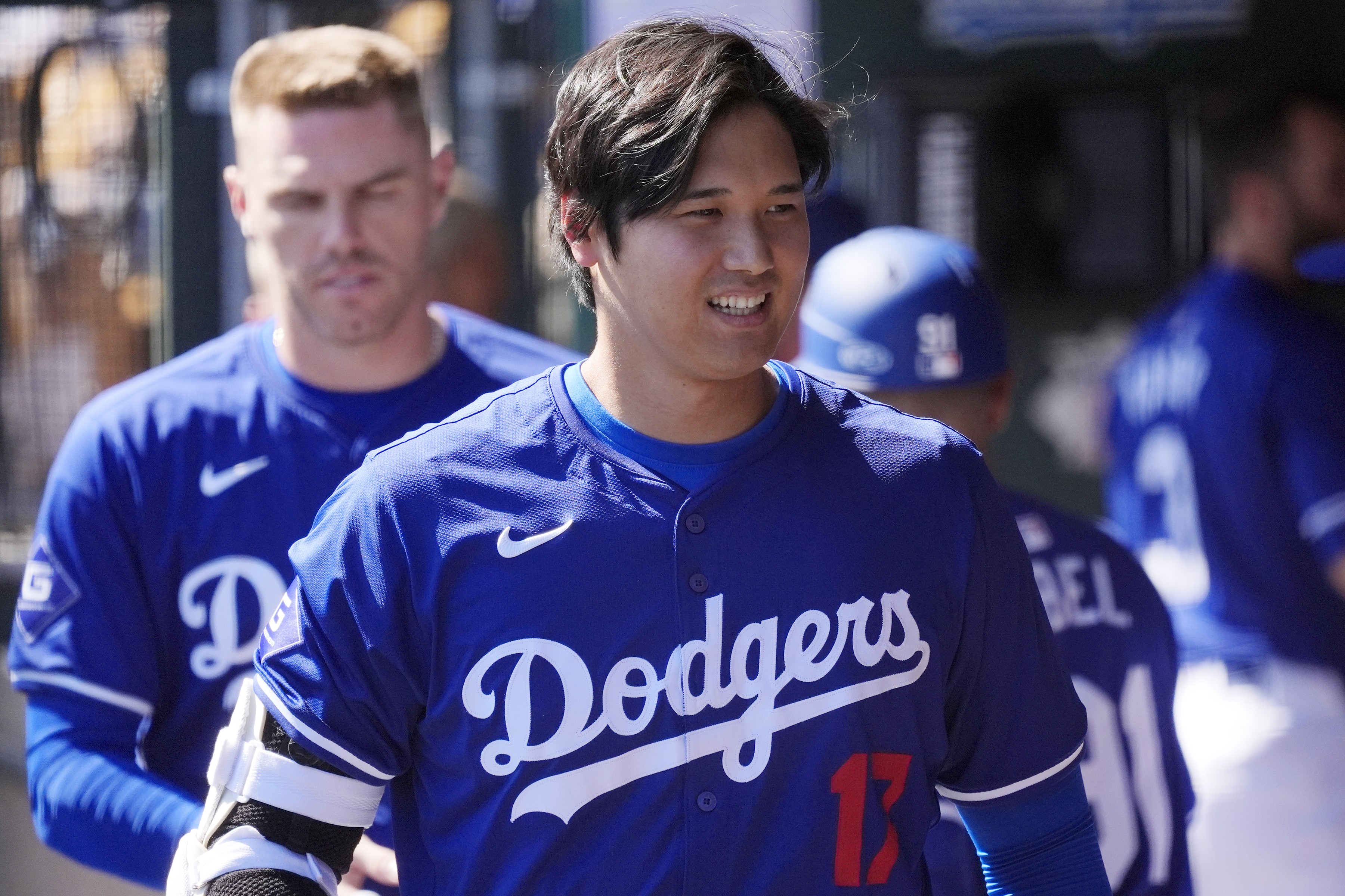 FILE - Los Angeles Dodgers' Shohei Ohtani, of Japan, walks through the dugout during the team's spring training baseball game against the Seattle Mariner, March 13, 2024, in Phoenix. Beginning with its ninth international opener, Major League Baseball is traveling all over the world in 2024. Ohtani and the Dodgers play Manny Machado and the San Diego Padres in Seoul, South Korea 
