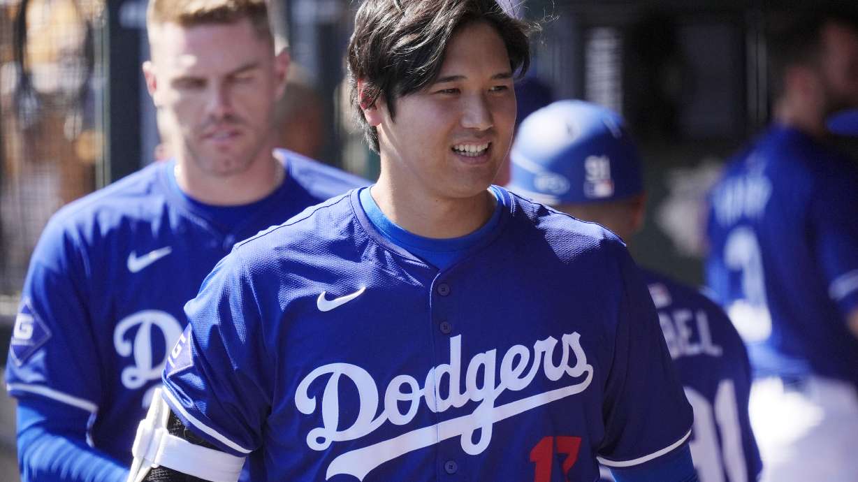 FILE - Los Angeles Dodgers' Shohei Ohtani, of Japan, walks through the dugout during the team's spring training baseball game against the Seattle Mariner, March 13, 2024, in Phoenix. Beginning with its ninth international opener, Major League Baseball is traveling all over the world in 2024. Ohtani and the Dodgers play Manny Machado and the San Diego Padres in Seoul, South Korea