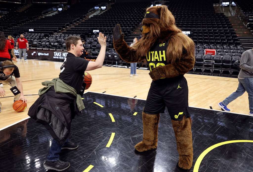 Jaren Karr high-fives Jazz Bear during an event for TURN Community Services' Utah County day program participants, hosted by Ken Garff Automotive, at the Delta Center in Salt Lake City on Thursday.