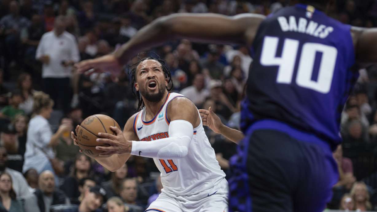 New York Knicks guard Jalen Brunson (11) pulls up for a shot as Sacramento Kings forward Harrison Barnes (40) runs over to defend in the first half of an NBA basketball game in Sacramento, Calif., Saturday, March 16, 2024.