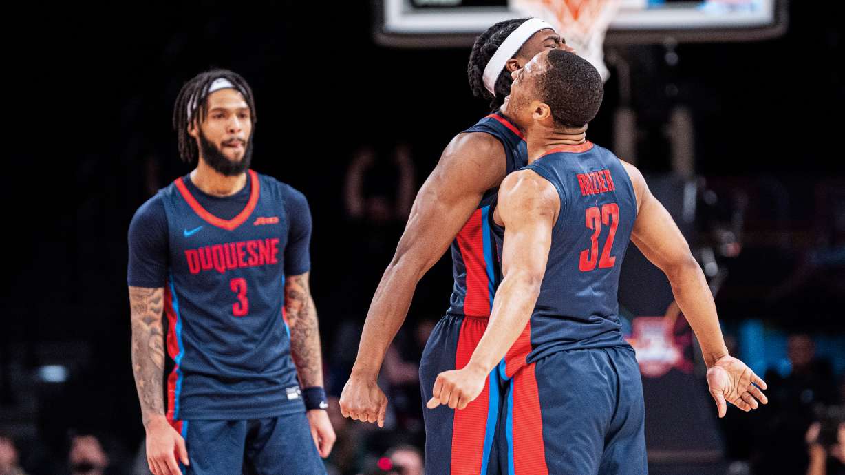 Duquesne's Kareem Rozier (32) celebrates with Jimmy Clark III, center, during the first half of an NCAA college basketball game against VCU in the championship of the Atlantic 10 Conference tournament on Sunday, March 17, 2024, in New York.