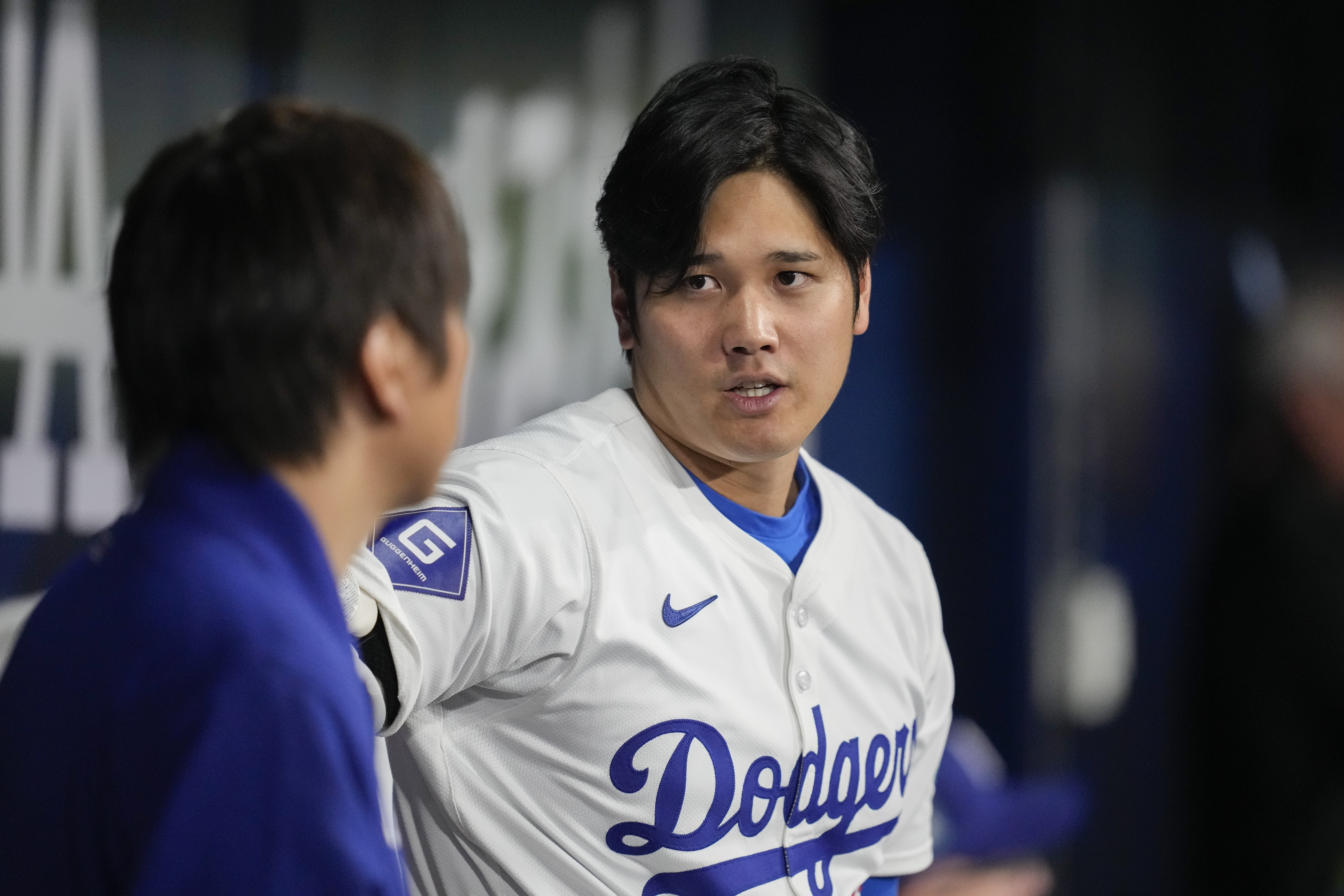 Los Angeles Dodgers' designated hitter Shohei Ohtani, right, chats with his interpreter during the first innings of an exhibition game between Team Korea and the Los Angeles Dodgers at the Gocheok Sky Dome in Seoul, South Korea, Monday, March 18, 2024.