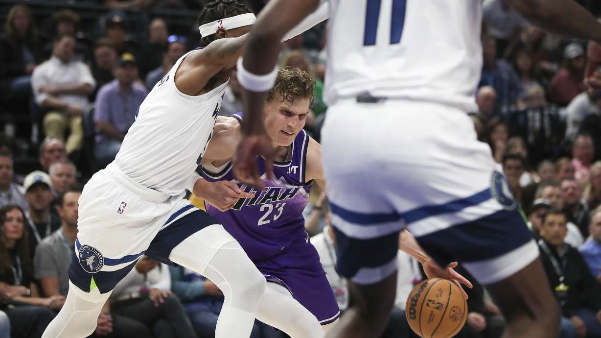 Utah Jazz forward Lauri Markkanen (23), center, dribbles through the defense of Minnesota Timberwolves forward Jaden McDaniels, left, and center Naz Reid (11) during the first half of an NBA basketball game Monday, March 18, 2024, in Salt Lake City.