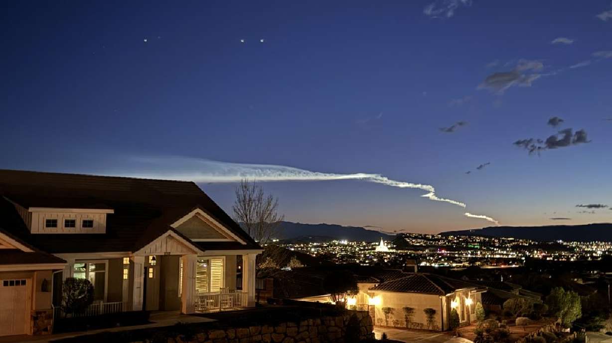 The streak of the launch from California of a Falcon 9 rocket carrying a batch of 20 Starlink satellites is seen above homes and the Red Cliffs Utah Temple in St. George, Monday.