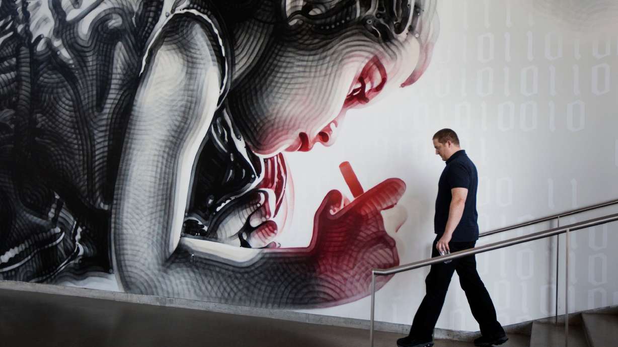An Adobe employee walks into the cafe next to spray-painted artwork at the Adobe office in Lehi on July 13, 2017.