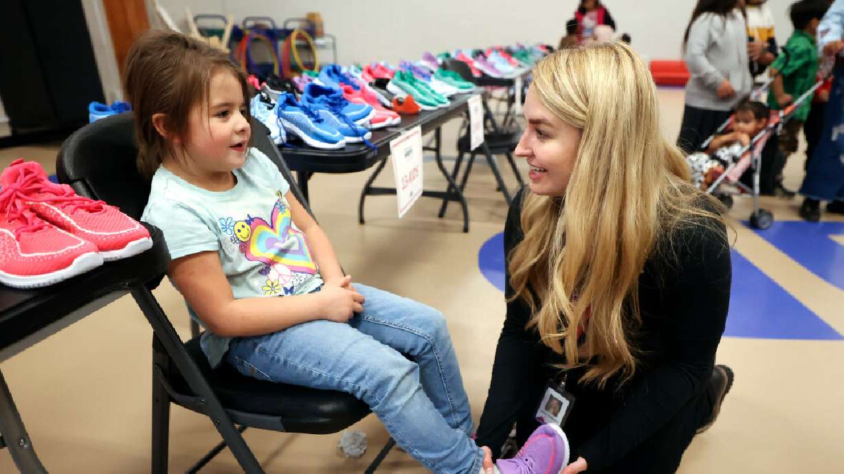 Amirah Garcia, 4, tries on a pair of shoes, donated by Mountain America Credit Union and Operation Warm, with Jenny Peterson, Mountain America event manager, at Ogden-Weber Community Action in Ogden on Tuesday.