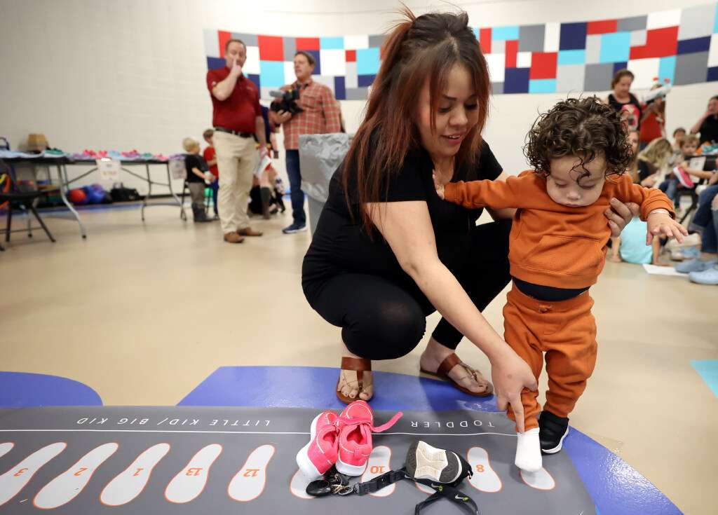 Arianny Alfaro tries to measure Francisco Alfaro’s shoe size before getting a pair of shoes, donated by Mountain America Credit Union and Operation Warm, at Ogden-Weber Community Action in Ogden on Tuesday.