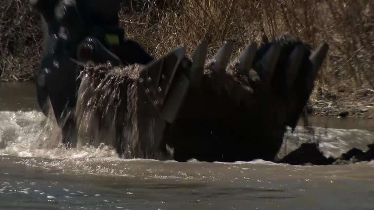 An excavator bucket full of sediment is pulled from the Logan River Wednesday.