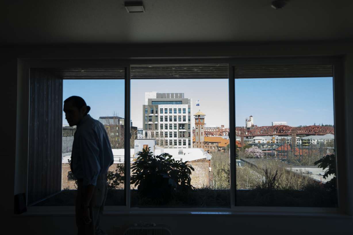 With a view of Portland, Ore., in the background, Cheyenne Welbourne walks in the common room at The Starlight affordable housing building that is run by Central City Concern, a Portland-based homeless services nonprofit, on March 15. Welbourne moved into one of the nonprofit's single room occupancy units in downtown Portland last March after years of living on the streets.