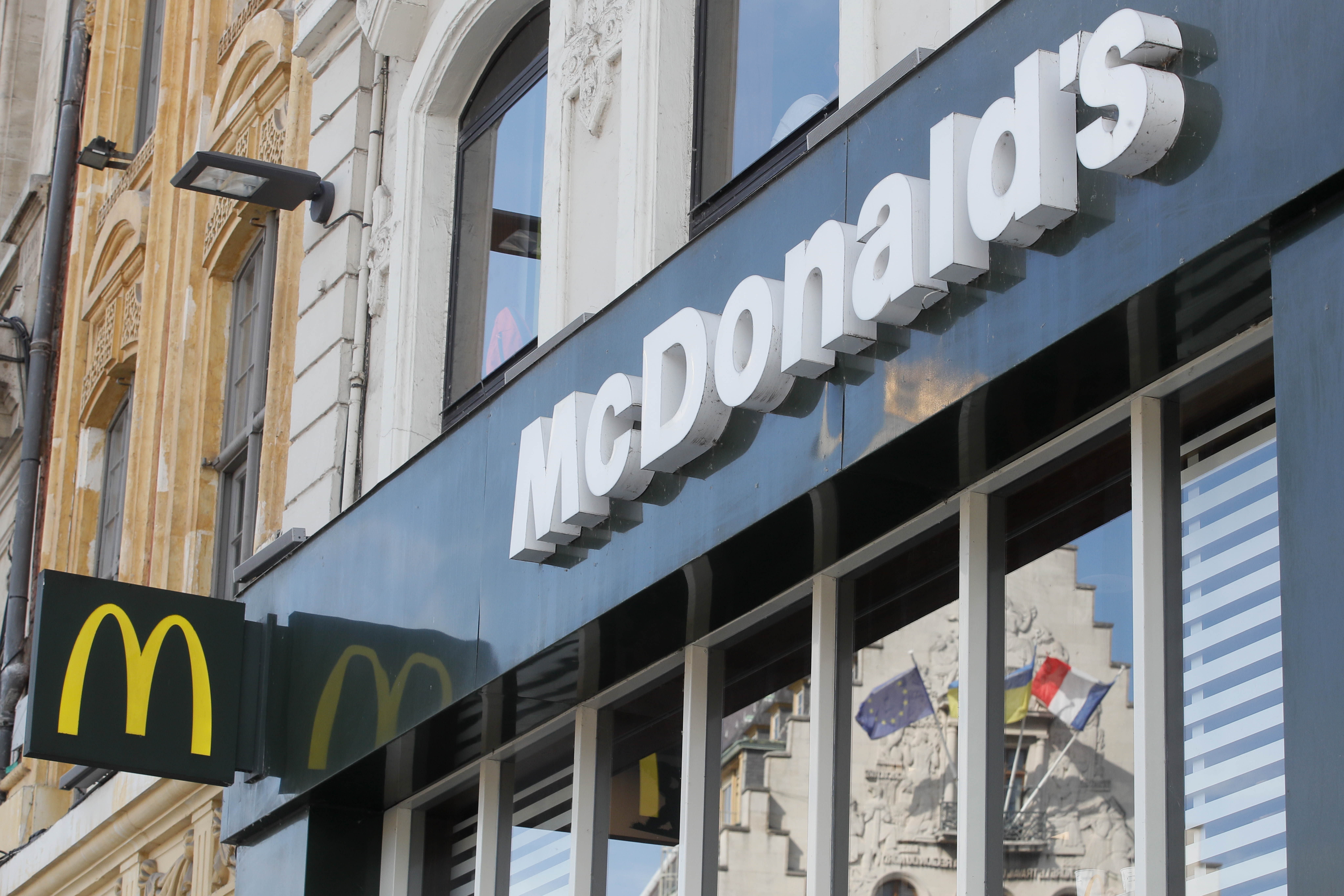 FILE - A French and a European flags are reflected in the shop window of a McDonald's restaurant in Lille, northern France, Thursday, June 16, 2022 . McDonald’s will become the title sponsor of the French soccer league from July for the next three seasons, the league said on Thursday, March 21, 2024. 