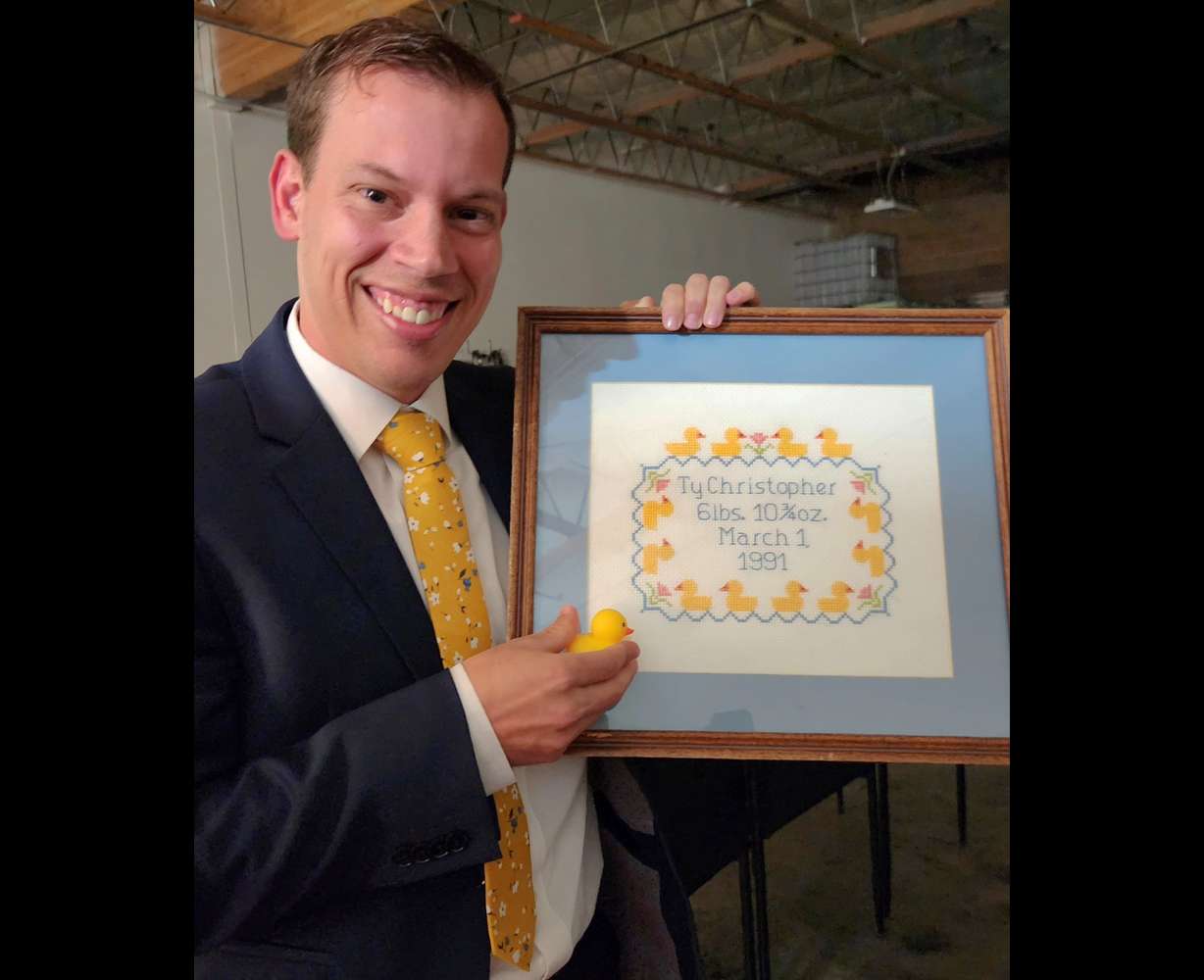 Ty Nelson poses with his cross-stitch that created a cult-like following of college students at a movie premiere in Orem on March 13.