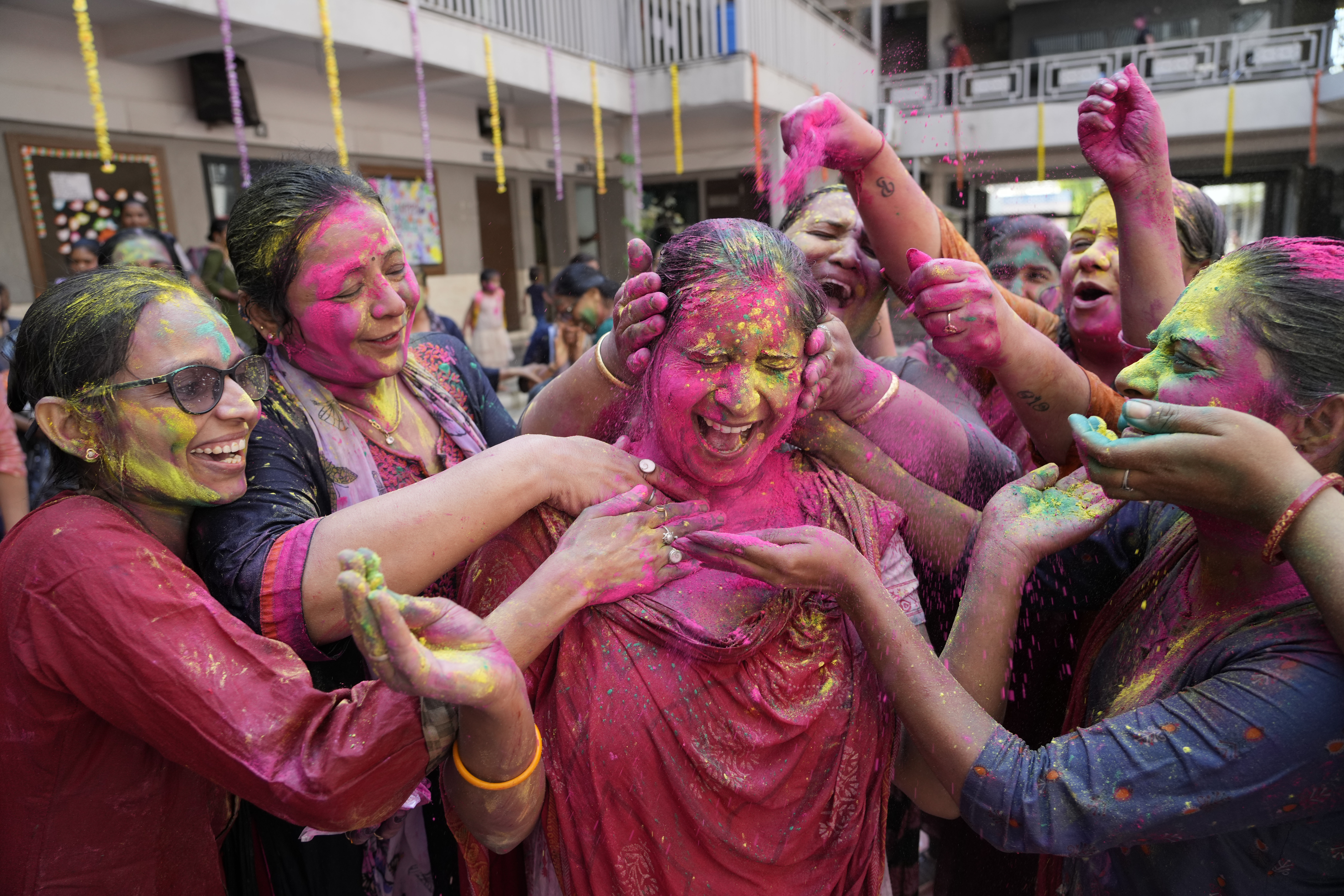 Teachers apply colored powder on another as they celebrate Holi, the Hindu festival of colors, at a school in Ahmedabad, India, March 17, 2022.