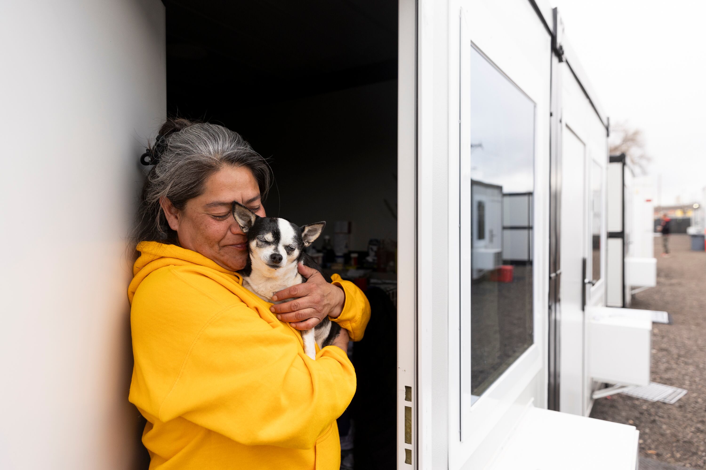 Jacqui Hatch poses with her dog Zoe outside her unit at the Switchpoint microshelter community in Salt Lake City on Thursday. The planned relocation of 25 microhousing units in Salt Lake City will likely be pushed back to mid-summer.