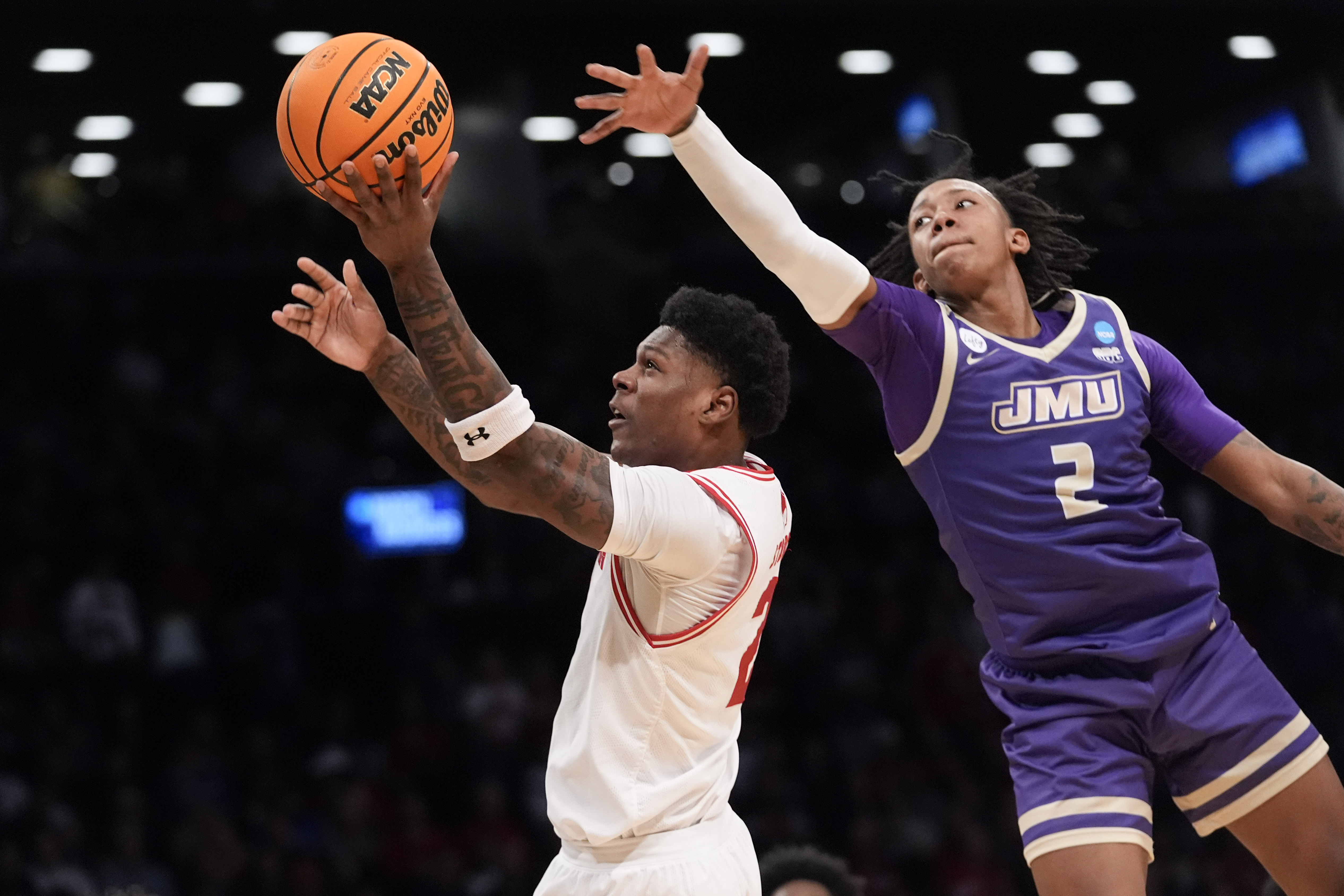 Wisconsin guard AJ Storr, left, goes to the basket against James Madison forward Raekwon Horton (2) during the first half of a first-round college basketball game in the men's NCAA Tournament, Friday, March 22, 2024, in New York. 