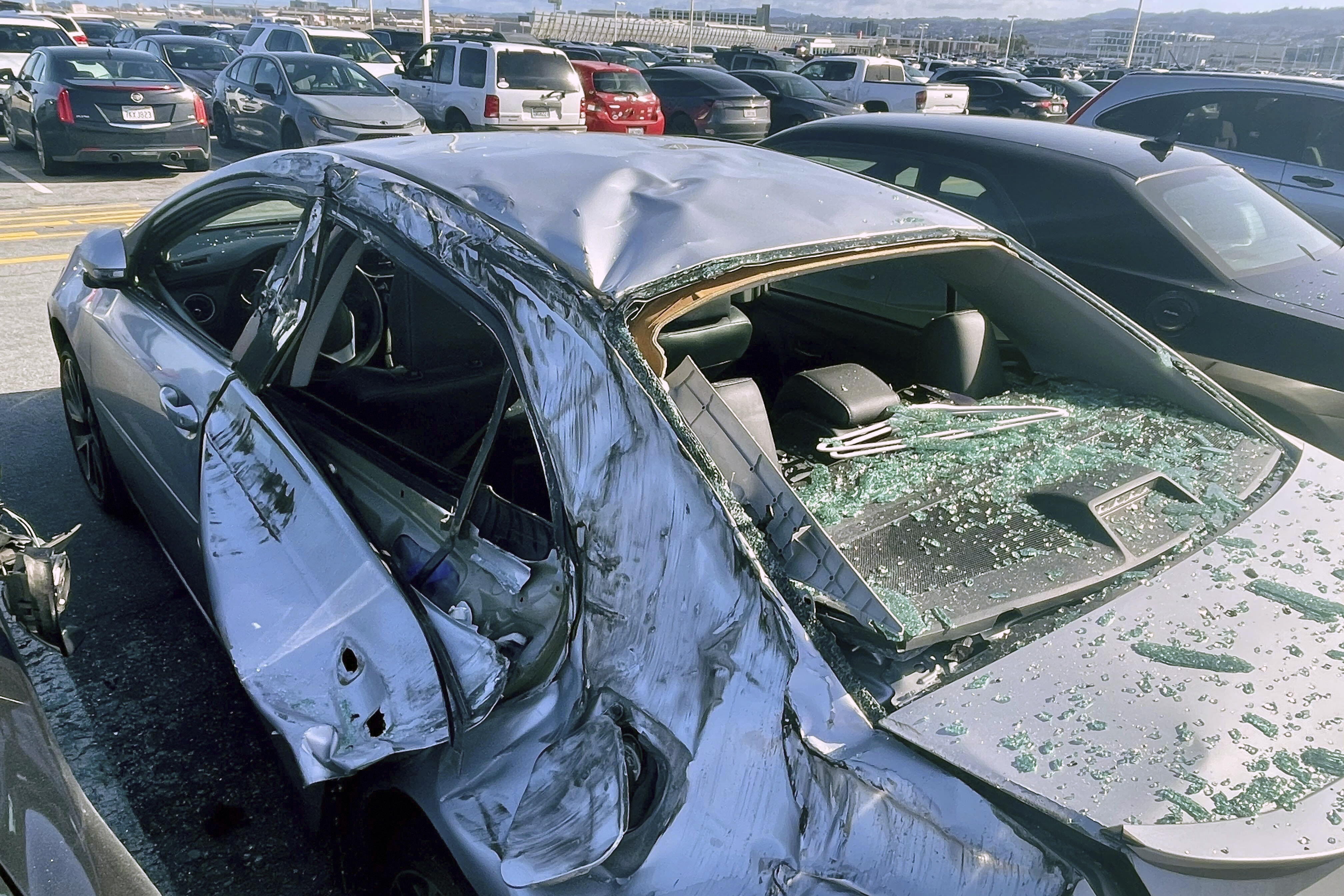 A damaged car is seen in a airport parking lot after debris from tire which fell from a Boeing 777 landed on it at San Francisco International Airport, March 7. Cracked windshields on jetliners and engine problems that cause flight delays don't normally attract much attention, but routine and rare problems with passenger planes are attracting an unusual amount of news coverage.