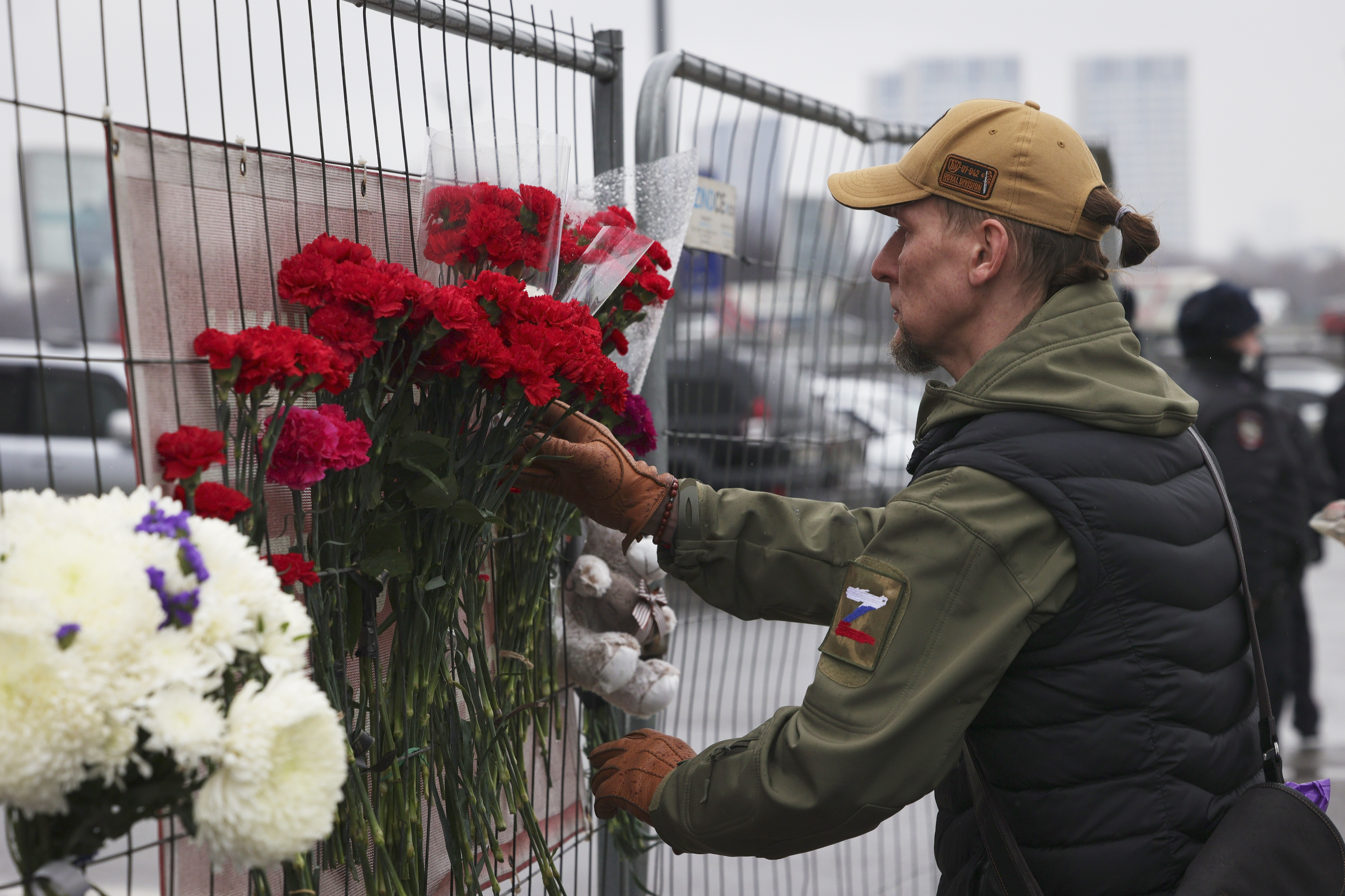 A man places flowers on the fence near the Crocus City Hall on the western edge of Moscow, Saturday, following an attack Friday, for which the Islamic State group claimed responsibility. Over 90 people were killed, including at least three children, authorities said.