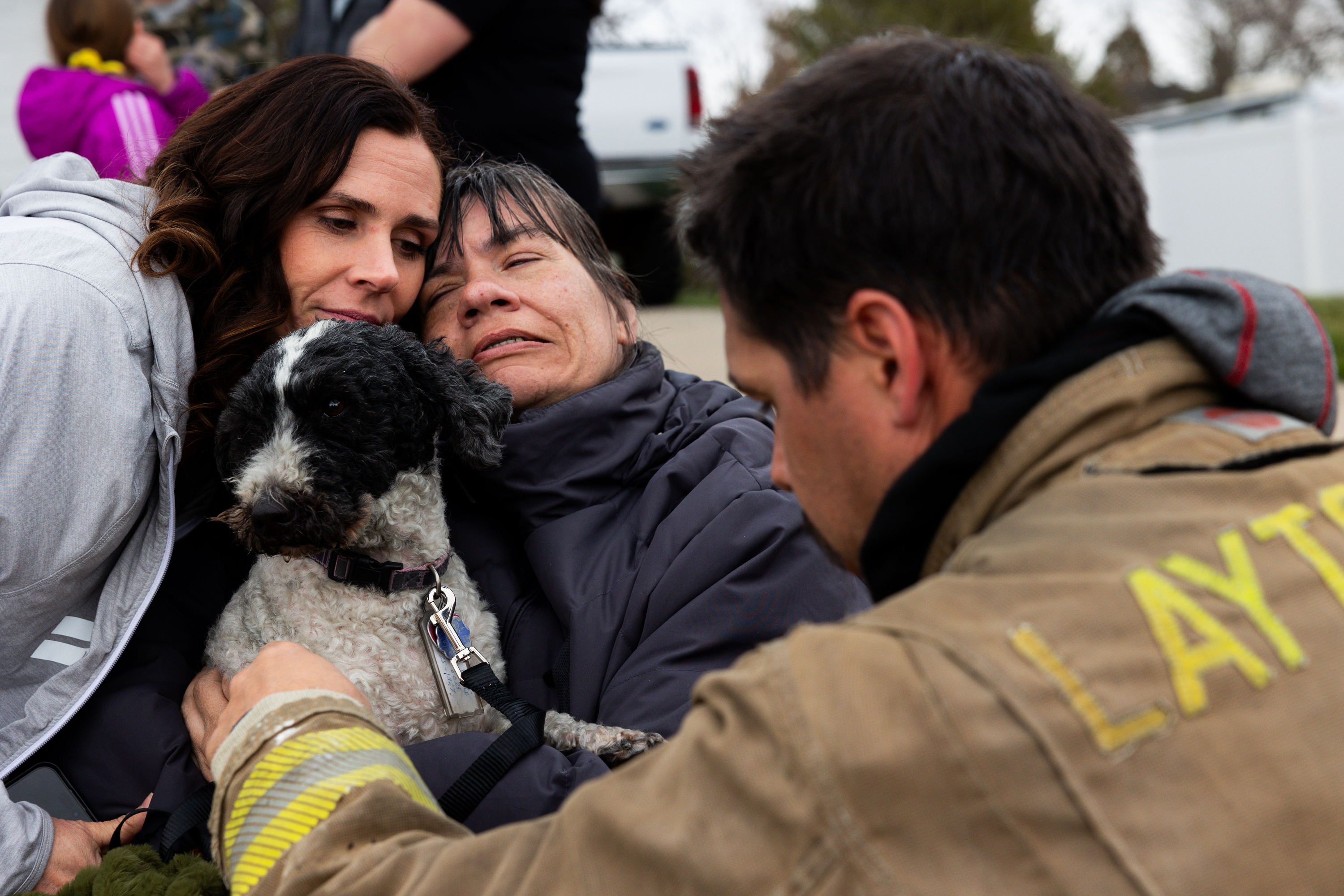 From left, Natalie Hawkes hugs her sister Debbie White and their dog while waiting outside while the fire department continue to work after putting out a fire at the home White lives at with her parents in Syracuse on Saturday.
